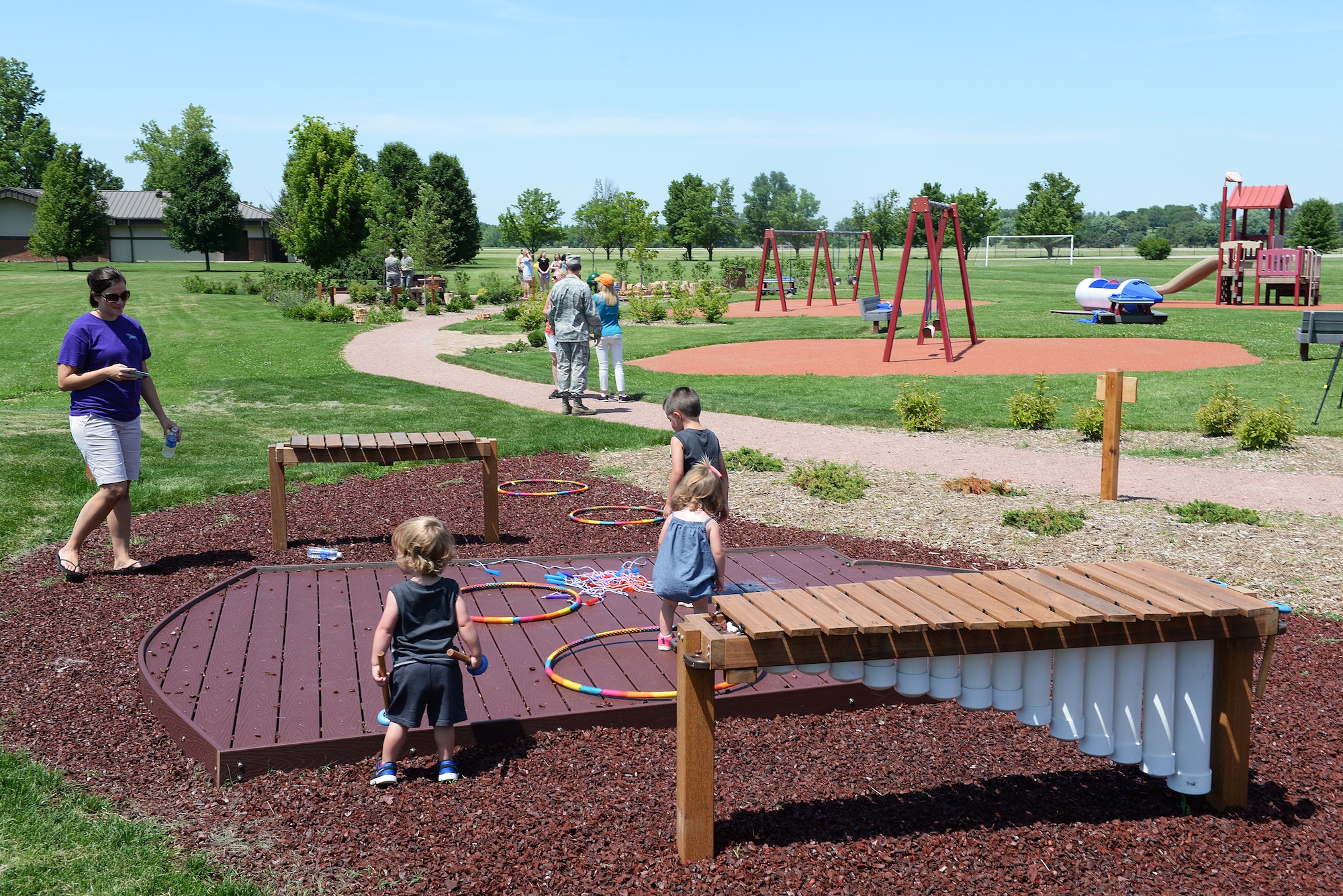 Families explore playground equipment recently installed at Warrior Park after the official ribbon cutting to open the new area June 10. The new additions are geared toward children with disabilities and young children. (U.S. Air Force photo/Senior Airman Joshua Eikren)