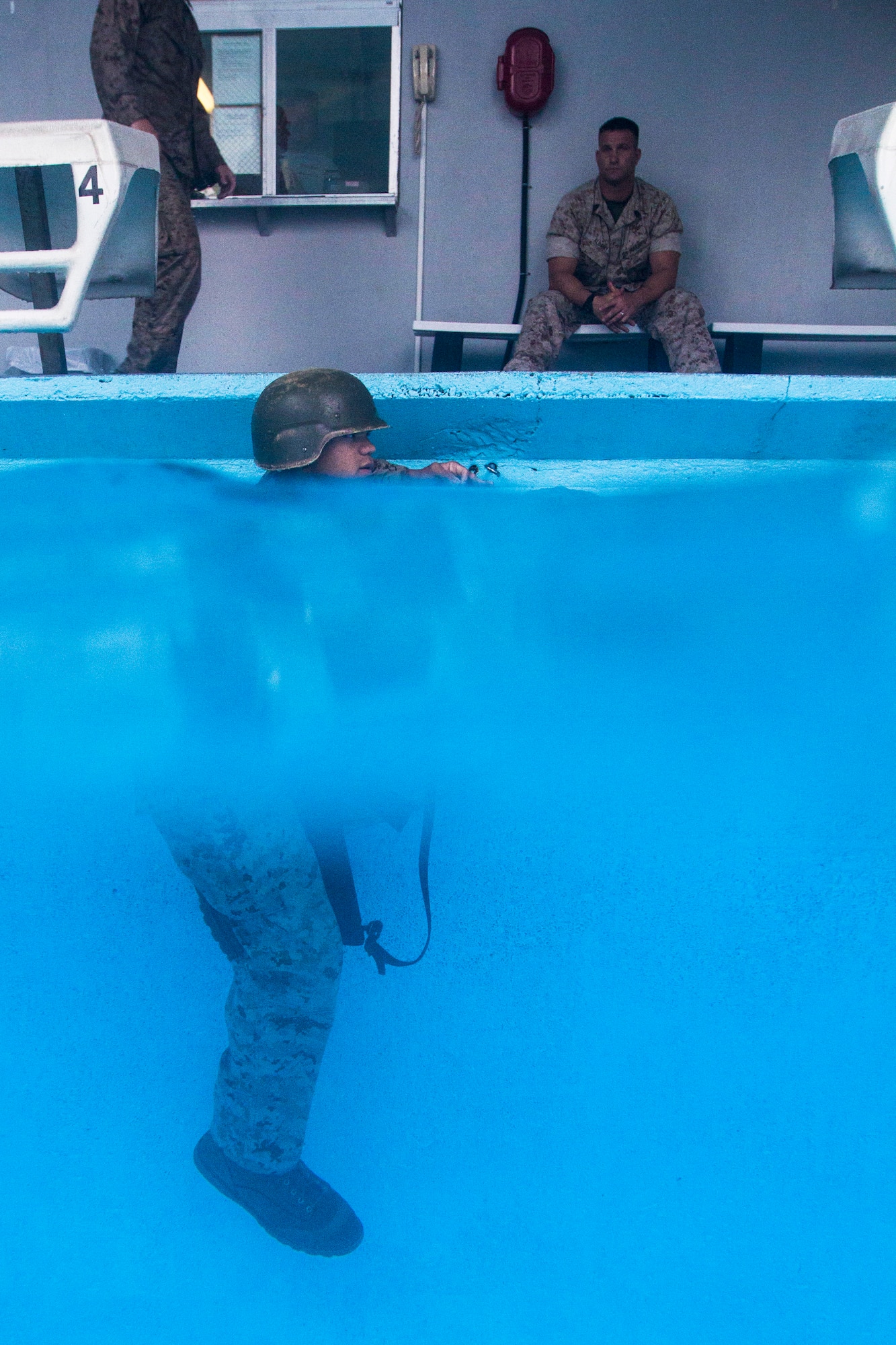 A U.S. Marine with the 3rd Battalion, 8th Marine Regiment holds onto the side of the pool before having to shed and retrieve his gear as part of the intermediate course of USMC Water Survival Training, June 10, 2015, at Camp Lejeune, North Carolina. Marines were given 20 seconds to completely submerse themselves and shed their gear, and then retrieve it from water 11 feet deep. (U.S. Air Force photo/Senior Airman Brittain Crolley)