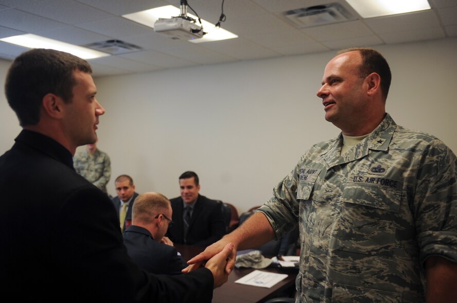 U.S. Air Force Brig. Gen. Kevin Givens, Air Force Office of Special Investigations commander, coins Special Agent Jacob Frank during his visit June 16, 2015, at Moody Air Force Base, Ga. During his visit, Givens held an all call where he addressed the agents and also answered any questions about future changes to the career field. (U.S. Air Force photo by Senior Airman Olivia Bumpers/Released)