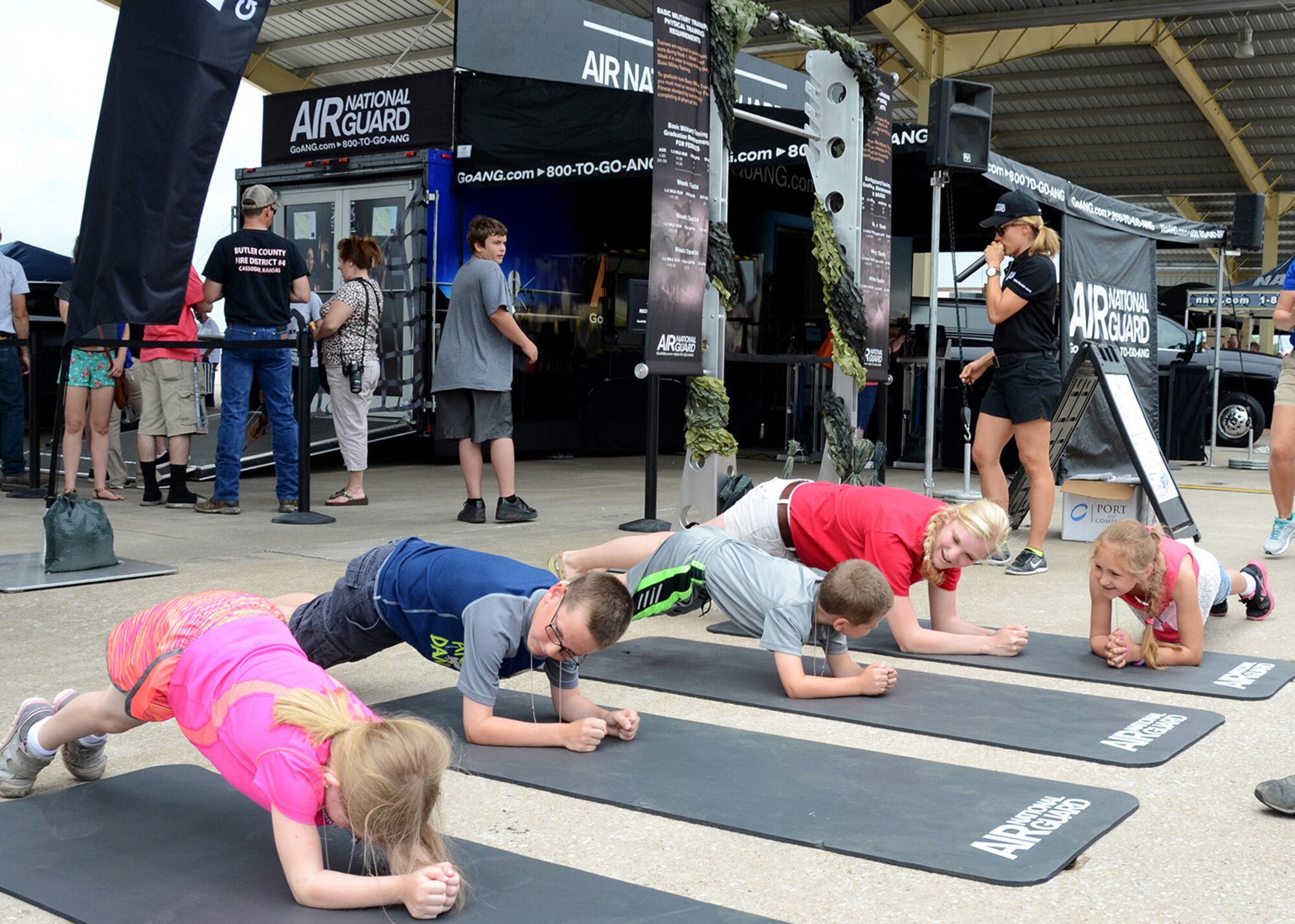 Airman 1st Class Cassidy Larson (red shirt), munitions technician from the 131st Maintenance Squadron, demonstrates a plank exercise with potential future members of the 131st Bomb Wing at the Missouri Air National Guard recruiting trailer at the Wings Over Whiteman air show June 13, 2015.  A number of Citizen-Airmen from the wing were on hand to support the two-day air show event.  (U.S. Air National Guard photo by Airman 1st Class Halley Burgess)