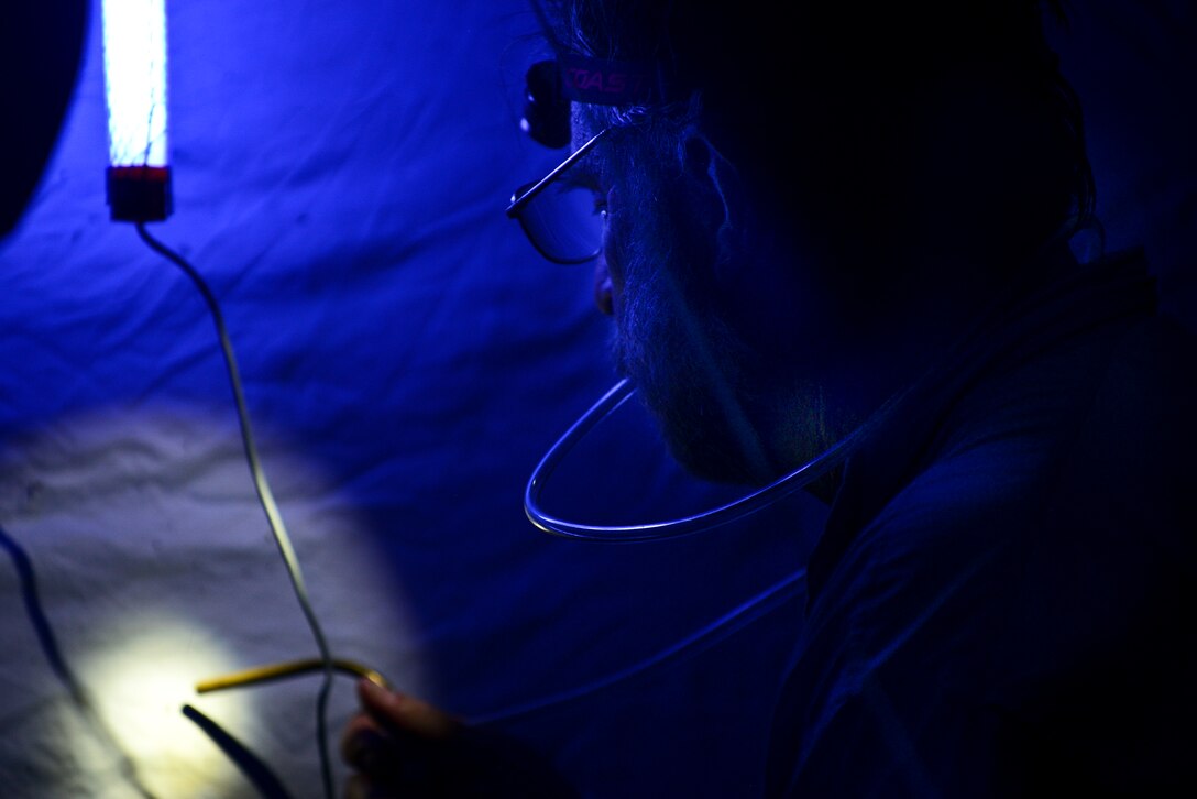 Dr. Art Evans, entomology researcher, uses a mouth-operated aspirator during a black light sheet insect collection at Fort Eustis, Va., June 12, 2015. Evans placed several traps throughout the installation’s forested training areas. The training areas are important because they reduce soil erosion, contribute to air quality which in turn provides recreational opportunities and aesthetics as well as resources for wildlife. (U.S. Air Force photo by Senior Airman Kimberly Nagle/Released)  