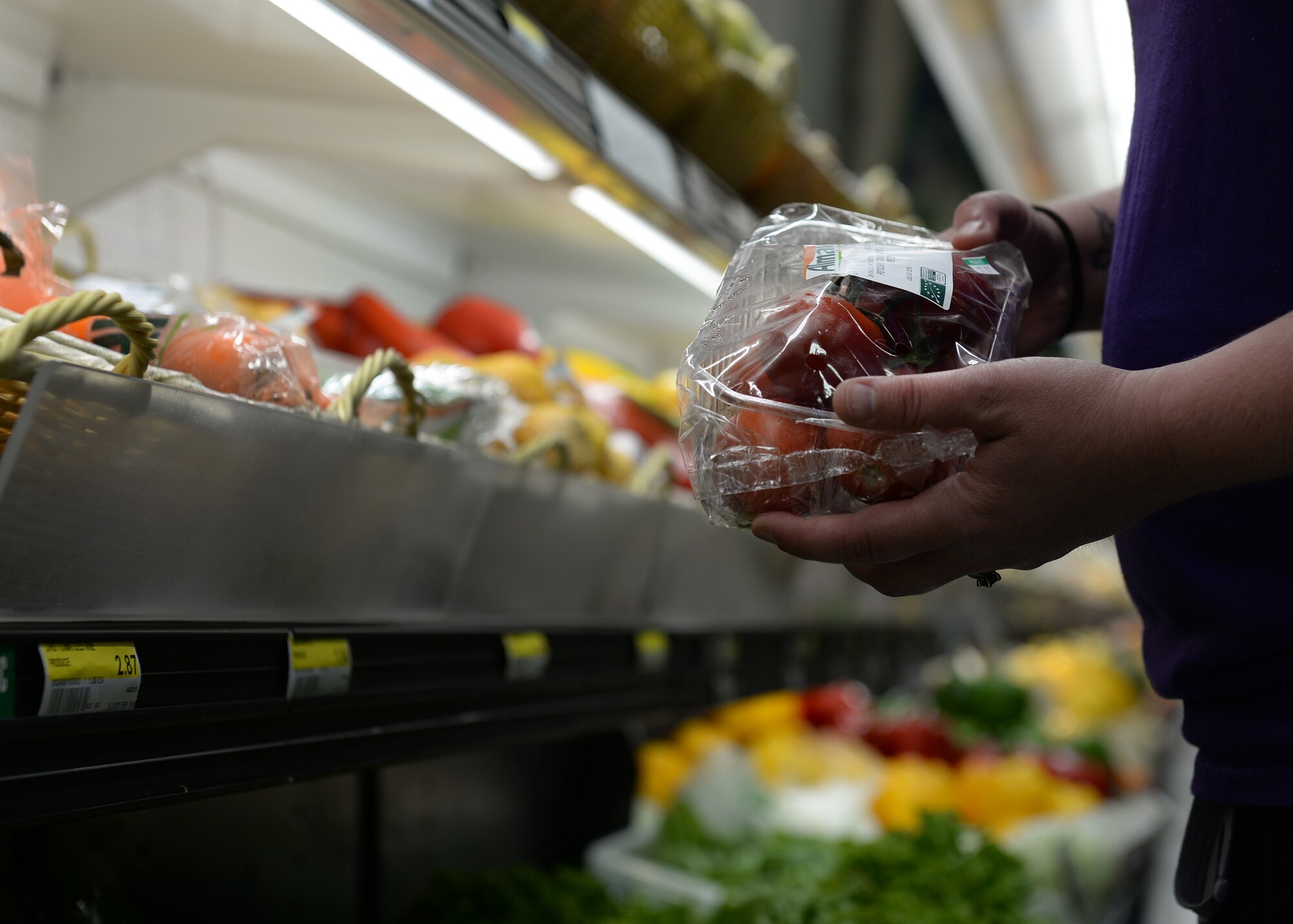 A commissary patron grabs a basket of organic tomatoes from the produce section, June 15, 2015, at Aviano Air Base, Italy. The commissary stocked its produce section with various organic fruit and vegetables from local suppliers. (U.S. Air Force photo by Airman 1st Class Cary Smith/Released)