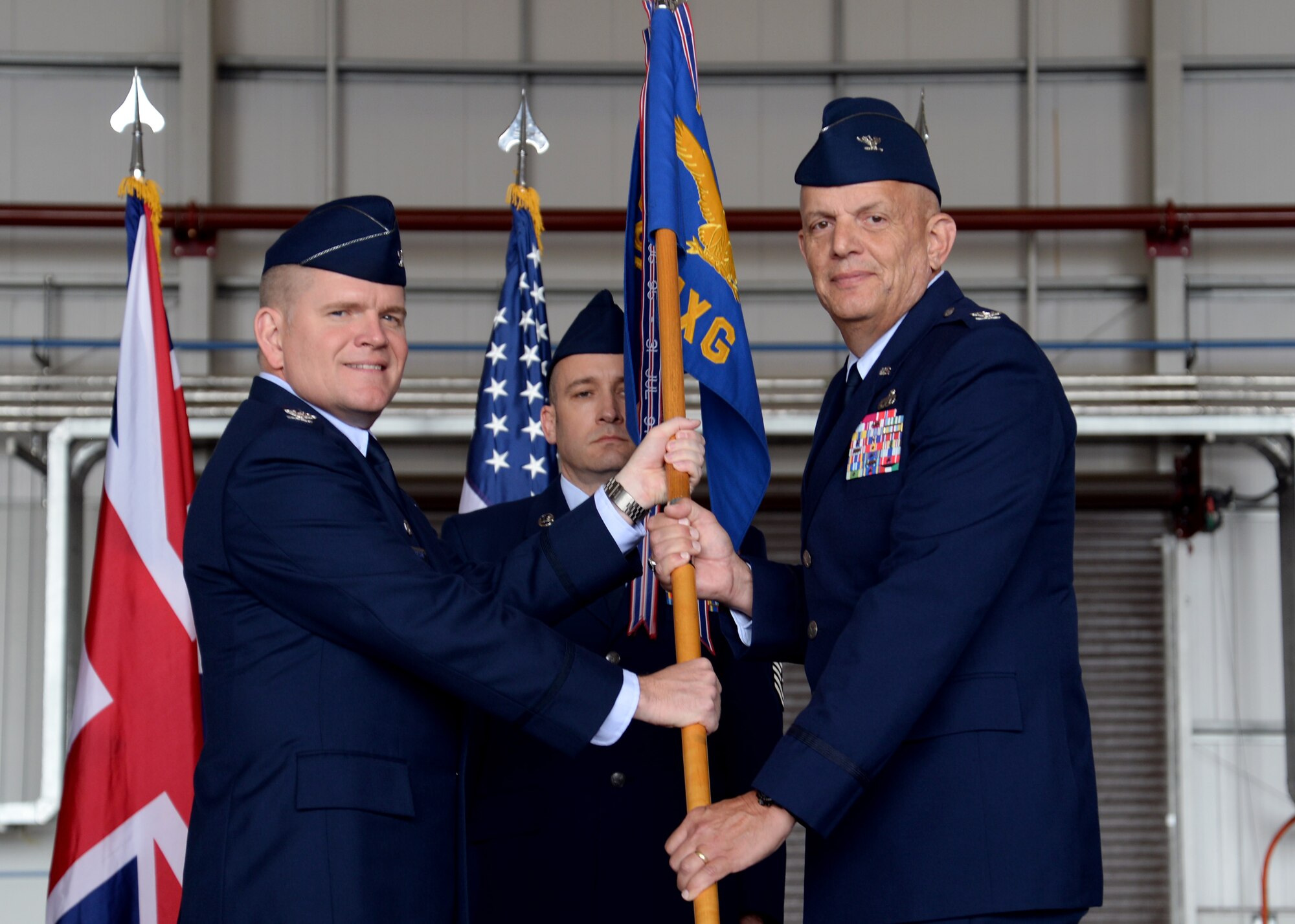 U.S. Air Force Col. Thomas D. Torkelson, left, 100th Air Refueling Wing commander, gives command of the 100th Maintenance Group to U.S. Air Force Col. Kelly Scott, incoming 100th MXG commander, during the 100th MXG change of command ceremony June 17, 2015, on RAF Mildenhall, England. The passing of the unit guidon during a change of command ceremony is a symbolic representation of passing authority to the incoming commander for all to see. (U.S. Air Force photo by Senior Airman Kyla Gifford/Released)
