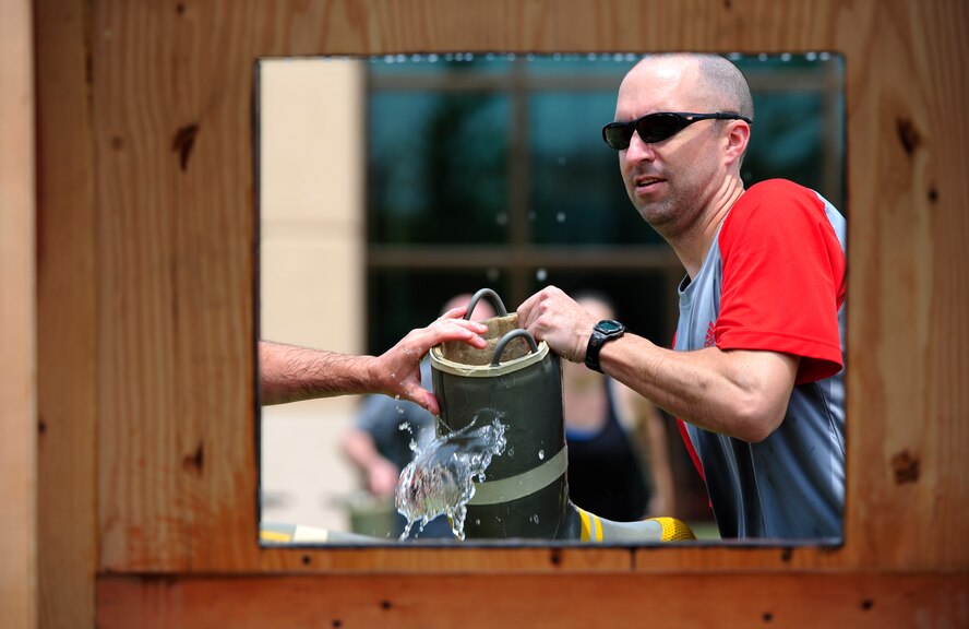 Master Sgt. Allen LeVie, 8th Civil Engineer Squadron 1st Sgt., participates in a bucket brigade game during a fire muster at the Wolf Pack Fitness Center on Kunsan Air Base, Republic of Korea, June 13, 2015. The fire muster gave Airmen from all over the wing an opportunity to test their fitness abilities against one another. (U.S. Air Force photo by Staff Sgt. Nick Wilson/Released)
