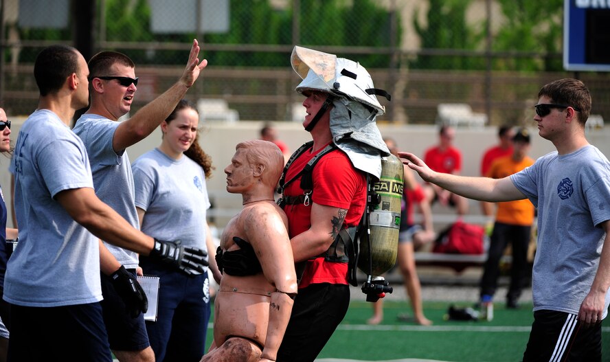 Trainers assist a firefighter from the 8th Civil Engineer Squadron as he participates in a 150-pound dummy drag during a fire muster at the Wolf Pack Fitness Center on Kunsan Air Base, Republic of Korea, June 13, 2015. The fire muster gave Airmen from all over the wing an opportunity to test their fitness abilities against one another. (U.S. Air Force photo by Staff Sgt. Nick Wilson/Released)
