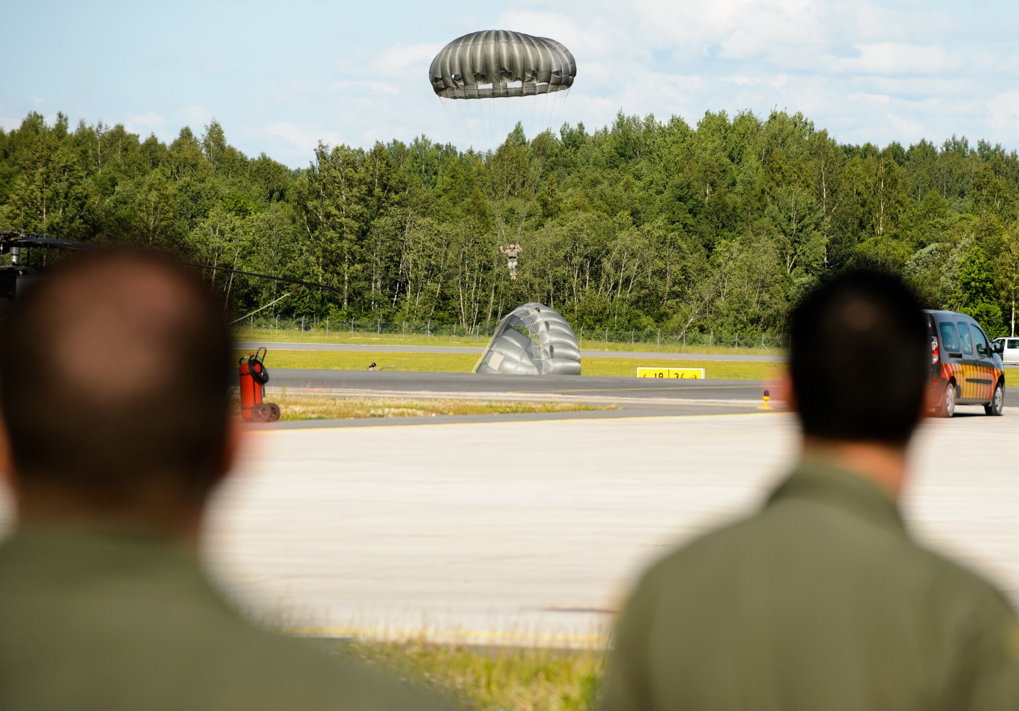 Pilots watch as U.S. Army members land during a combined jump day with the Latvian armed forces June 15, 2015, Lielvarde Air Base, Latvia. More than 70 U.S. Air Force, U.S. Army and Latvian service members participated in a jump day to strengthen the bonds of allies and learn from each other during exercise Saber Strike 15. The exercise involves more than 6,000 service members from 14 nations participation all throughout Estonia, Latvia, Lithuania, and Poland to learn from each other and promote stability is the region. (U.S. Air Force photo/ Staff Sgt. Armando A. Schwier-Morales)