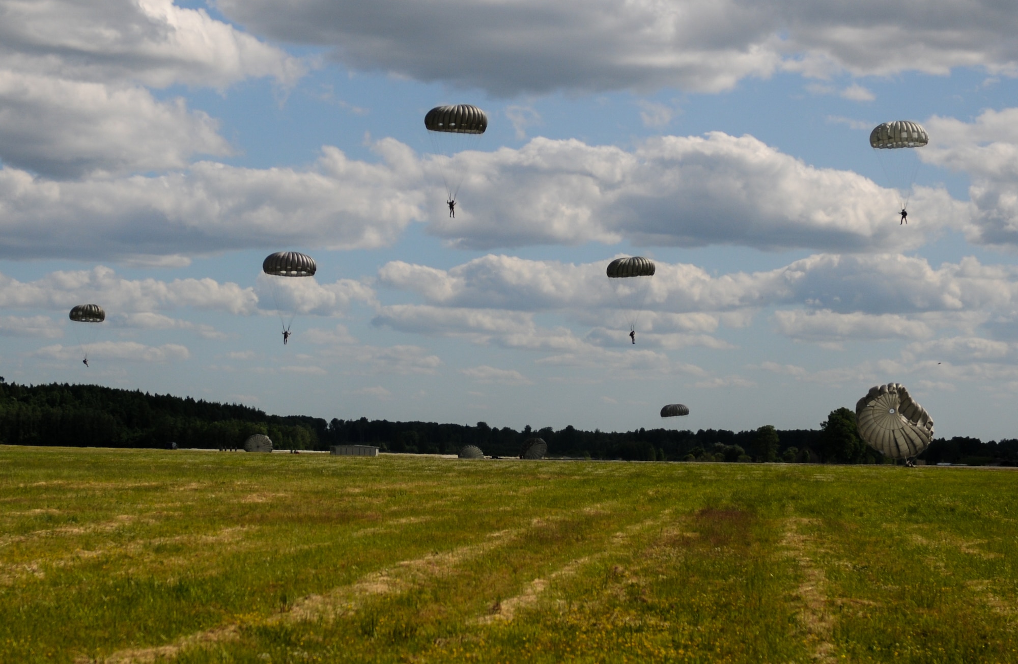 Multinational jumpers prepare to land after being air dropped by 37th Airlift Squadron, Ramstein Air Base, Germany, C-130J Super Hercules aircraft June 15, 2015, Lielvarde Air Base, Latvia. More than 70 U.S. Air Force, U.S. Army and Latvian service members participated in a multinational jump day to strengthen the bonds of allies and learn from each other during exercise Saber Strike 15. The exercise involves more than 6,000 service members from 14 nations participation all throughout Estonia, Latvia, Lithuania, and Poland to learn from each other and promote stability is the region. (U.S. Air Force photo/ Capt. Chase P. McFarland)