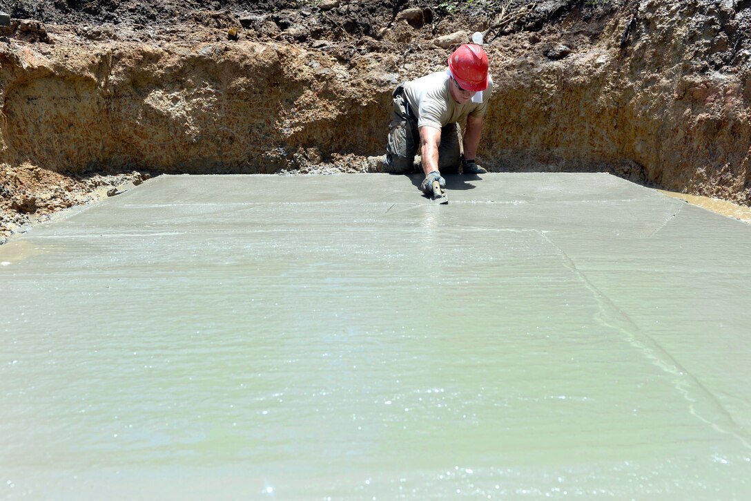 U.S. Air Force Staff Sgt. Edward Gimzhevskiy works to smooth the surface of a septic tank base at the Gabriela Mistral primary school construction site in Ocotes Alto, Honduras, June 11, 2015.