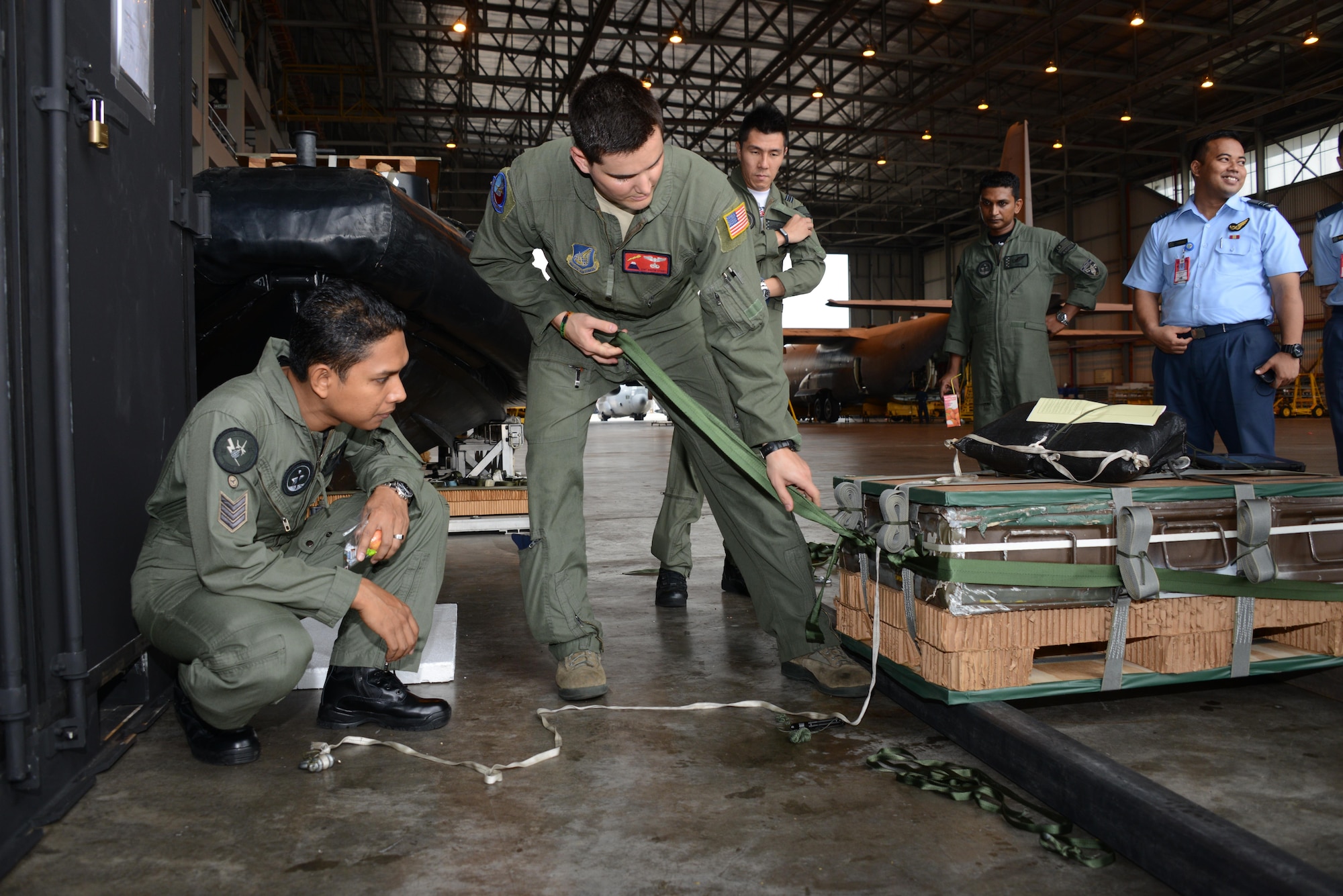 On right, U.S. Air Force Staff Sgt. Austin Storrs, a loadmaster from the 36th Airlift Squadron at Yokota Air Base, Japan, shows a loadmaster from the Royal Malaysia Air Force how his conducts low-cost low-altitude air drops from a C-130H during a focus exchange class held June 2, 2015 at Subang Air Base in Malaysia.  Crews from the 36th AS conducted the LCLA class as part of a focus exchange during Joint Chiefs of Staff Exercise Teak Mint.  (U.S. Air Force photo by Tech. Sgt. Kristine Dreyer)