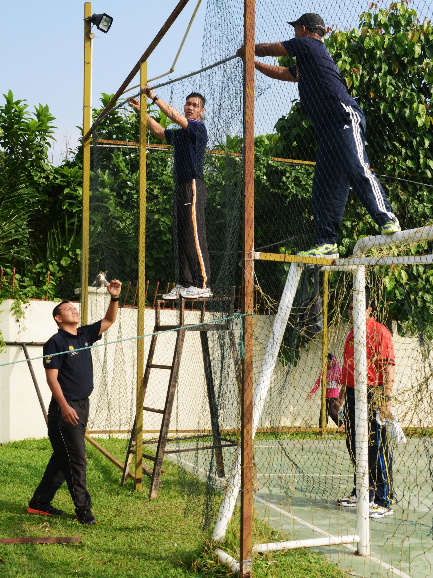 Members from the Royal Malaysian Air Force repair fencing around the soccer pitch at the Rumah Kasih Hormoni Orphanage near Kuala Lumpur, Malayasia, June 6, 2015 As part of Exercise Teak Mint, members from the RMAF, U.S. Air Force came together to help with repairs around the orphanages and  donated more than  $1,000 in clothes, games and sports equipment.  (U.S. Air Force Tech. Sgt. Kristine Dreyer)