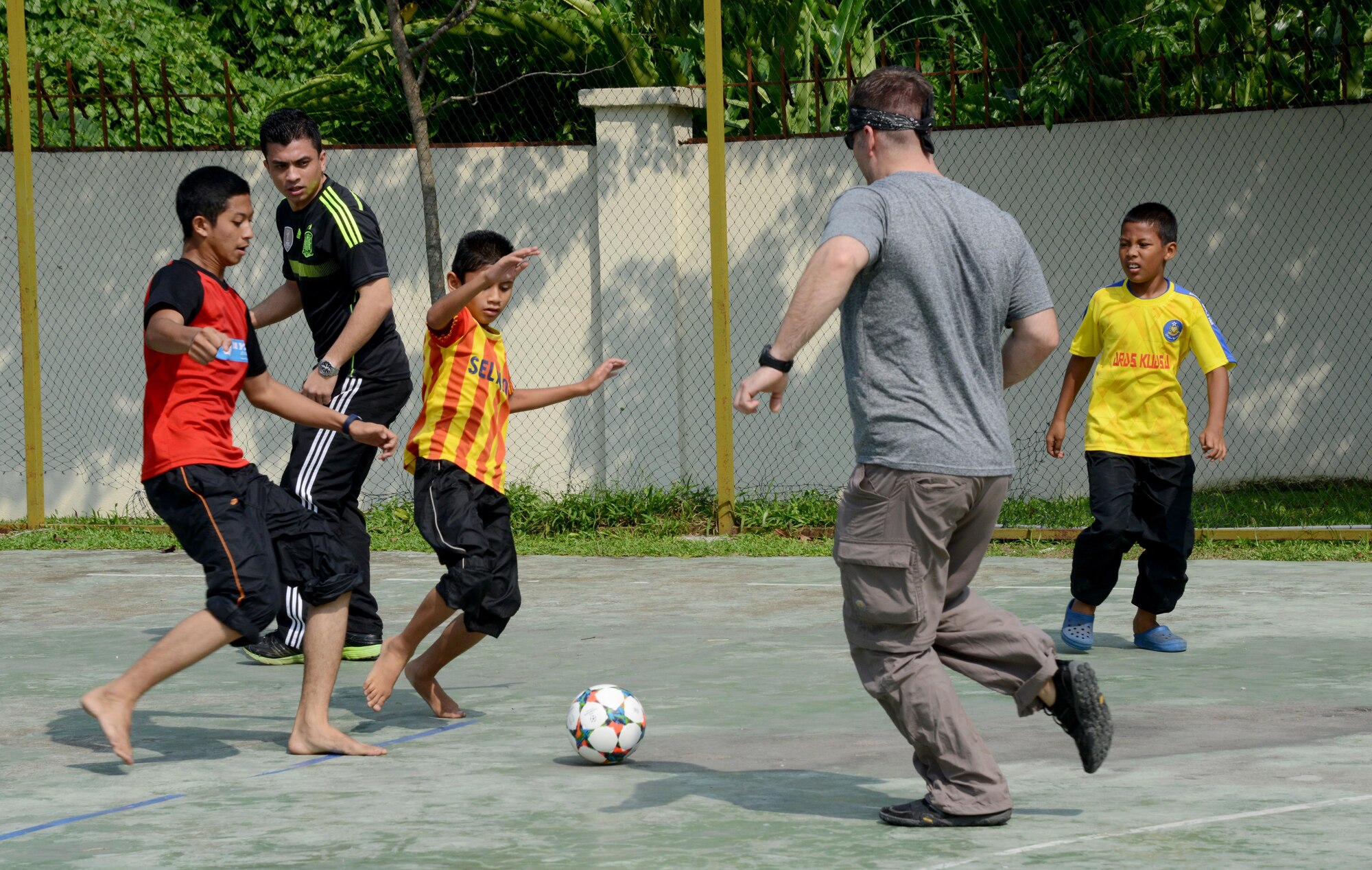 Tech. Sgt. Ryan Moore a loadmaster with the 17th Special Operations Squadron and a member from the Royal Malaysian Air Force play soccer with the children at the Rumah Kasih Hormoni Orphanage near Kuala Lumpur, Malaysia, June 6, 2015.  As part of Exercise Teak Mint, members from the RMAF, U.S. Air Force came together to help with repairs around the orphanage and donated more than $1,000 in clothes, games and sports equipment.  (U.S. Air Force photo by Tech. Sgt. Kristine Dreyer)