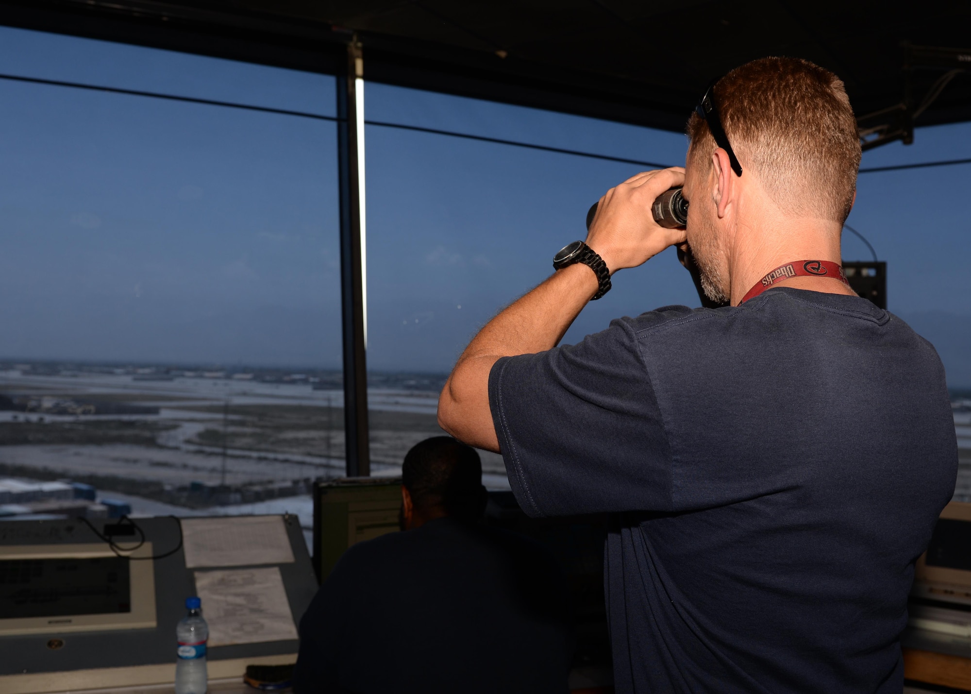 Douglas Mack looks through his binoculars to see incoming aircraft while working at the air traffic control tower June 17, 2015, at Bagram Airfield, Afghanistan. Mack is a part of the Midwest Air Traffic Control team that has managed Bagram’s air traffic since 2003. (U.S. Air Force photo by Senior Airman Cierra Presentado/Released)