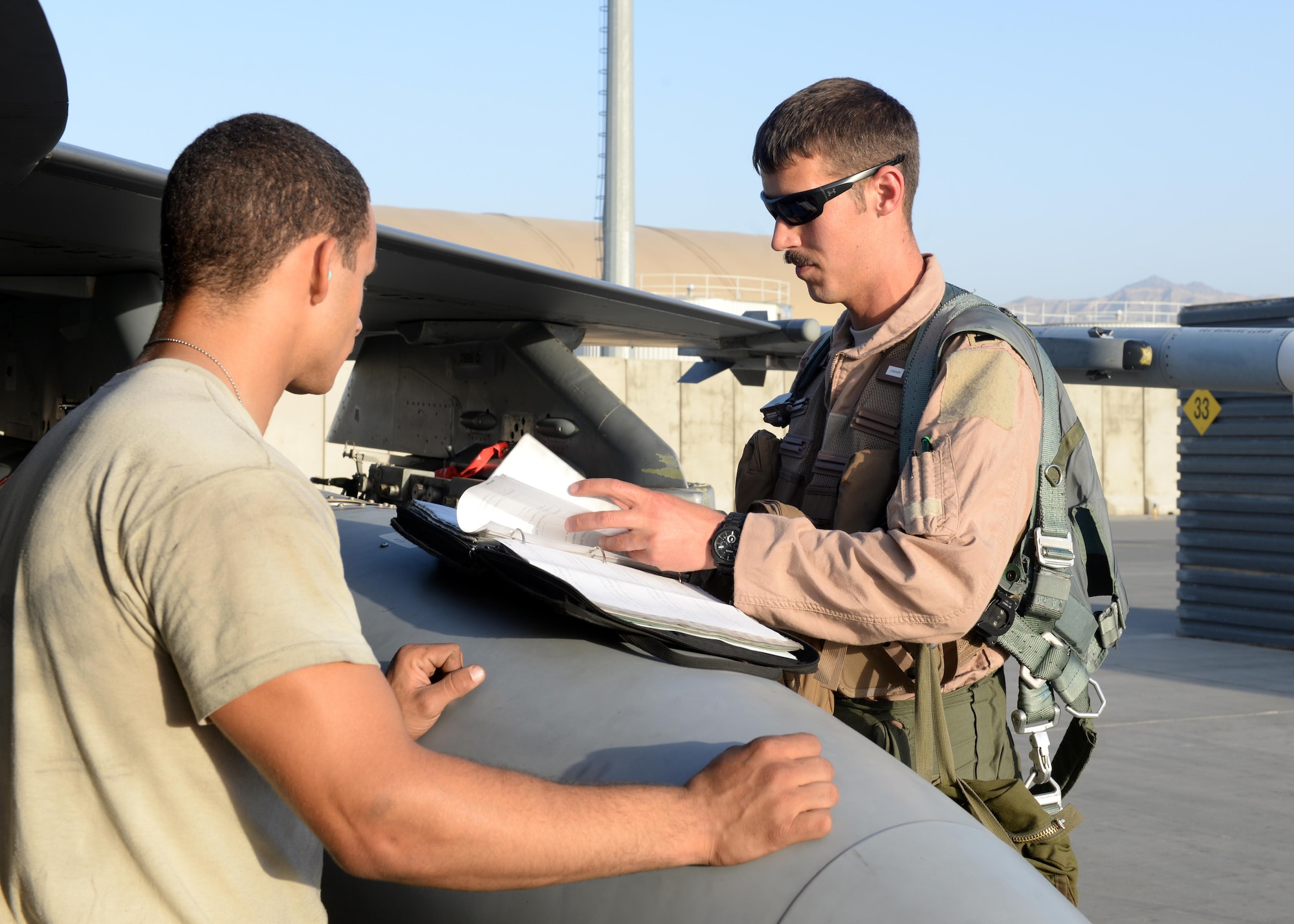 U.S. Air Force Capt. Dakota Olsen, 555th Expeditionary Fighter Squadron F-16 Fighting Falcon pilot, goes over flight information with an F-16 crew chief June 17, 2015, at Bagram Airfield, Afghanistan. Olsen’s job is to provide close air support and armed over watch for military personnel in Afghanistan. He flies various sorties and missions throughout the country on a daily basis providing airpower to ensure a safe and secure environment for personnel at BAF. (U.S. Air Force photo by Senior Airman Cierra Presentado/Released)