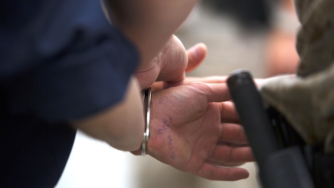 A Marine with the Provost Marshal’s Office on Camp Courtney, Okinawa, Japan, places handcuffs on an Uruma City police officer posing as an on-base intruder, June 11, 2015 during bilateral training between service members and the UCPD. The event ensured Marines with camp guard and the Provost Marshal’s Office are proficient in communicating with the UCPD to mitigate threats involving service members and Okinawa residents. During the training event, Camp Guard Marines patrolling the base perimeter apprehended a simulated armed intruder. PMO Marines received a notification over a radio signal and responded to rehearse turnover procedures of the intruder and escort him to the proper detainment authorities.