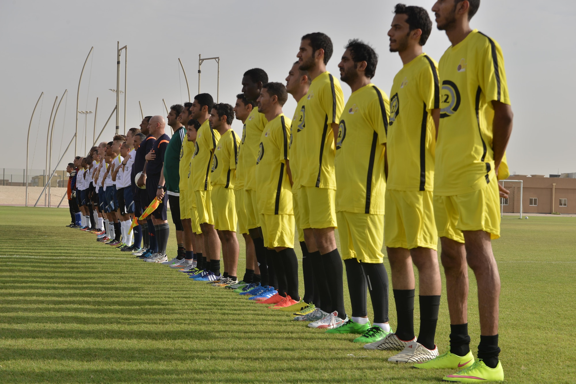 Deployed U.S. and Qatari military members stand as both national anthems are played prior to the start of a soccer match in celebration of the 240th U.S.  Army birthday June 14, 2015 at Al Udeid Air Base, Qatar. AUAB All-Stars planned a soccer match to help strengthen the partnership between the U.S. and Qatari military and build friendships between service members. (U.S. Air Force photo/Staff Sgt. Alexandre Montes)