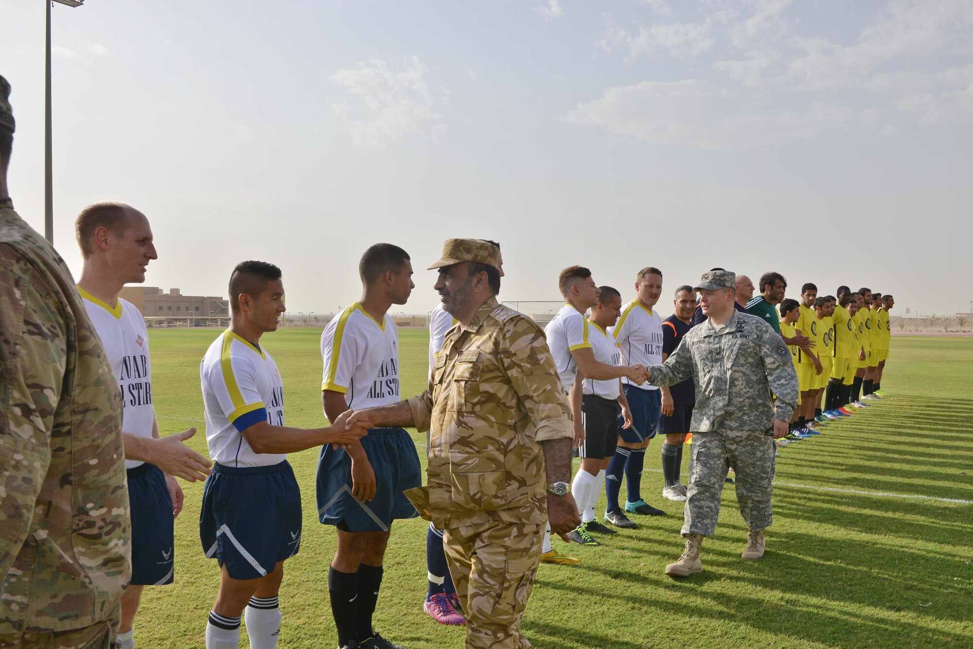 Qatari Brig. Gen. Fahad Al-Eraik, Al Udeid Air Base commander, and U.S. Army  Col. Jeff Merinkov, Camp As Sayliyah commander, shake hands and greet each player from both the Qatari and Al Udeid teams during the opening of soccer match in celebration of the 240th U.S.  Army birthday June 14, 25015 at Al Udeid Air Base, Qatar. AUAB All-Stars planned a soccer match to help strengthen the partnership between the U.S. and Qatari military and build friendships between service members. (U.S. Air Force photo/Staff Sgt. Alexandre Montes)