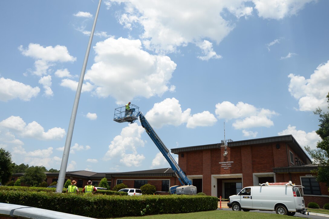 Bubba Hart, technician, Facility Improvement Services, is hoisted approximately 85 feet into the air to investigate a maintenance issue with the flag pole in front of Marine Corps Logistics Base Albany’s Coffman Hall, June 17.