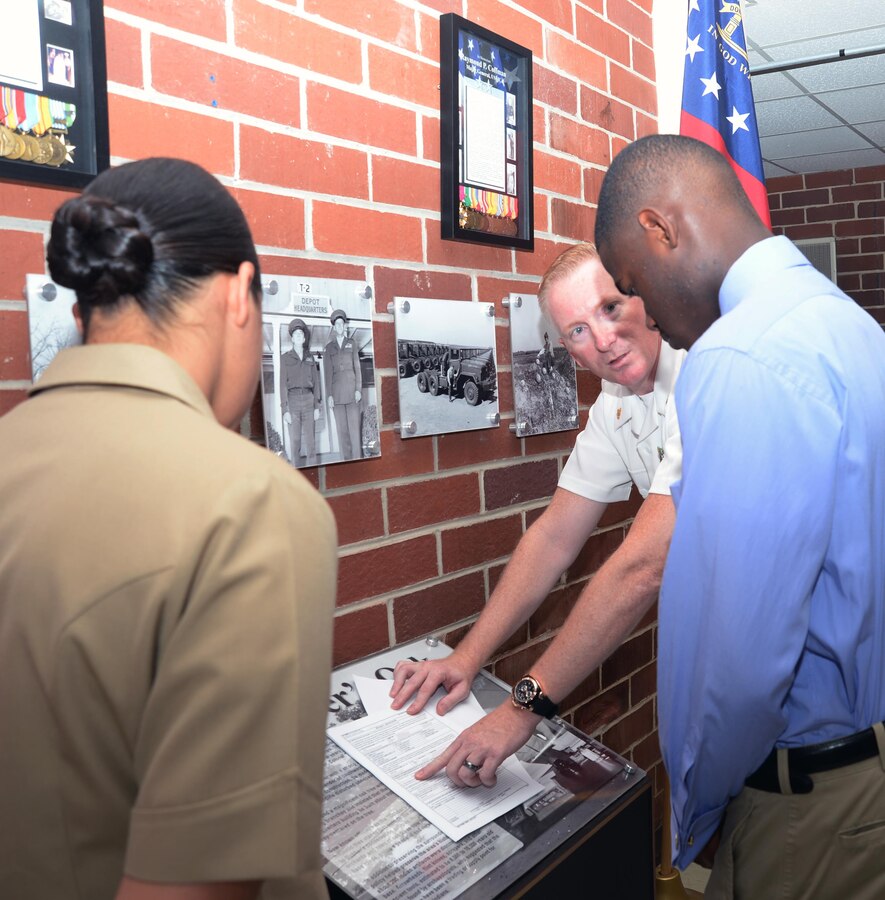 Leading Chief Petty Officer Brett Yahn, Navy Recruiting Station Albany, Ga. (right), explains enlistment papers to Jawaun Stanley, a Lee County High School graduate, (center) in Marine Corps Logistics Base Albany's Coffman Hall, June 17. Capt. Rene Barber, project manager, Marine Corps Systems Command-Albany, (left) rendered the oath to the 18-year-old in front of his parents, Marines, Navy recruiters and civilian-Marines. Stanley will attend the Naval Academy Preparatory School in Rhode Island before attending the U.S. Naval Academy in Annapolis, Md.