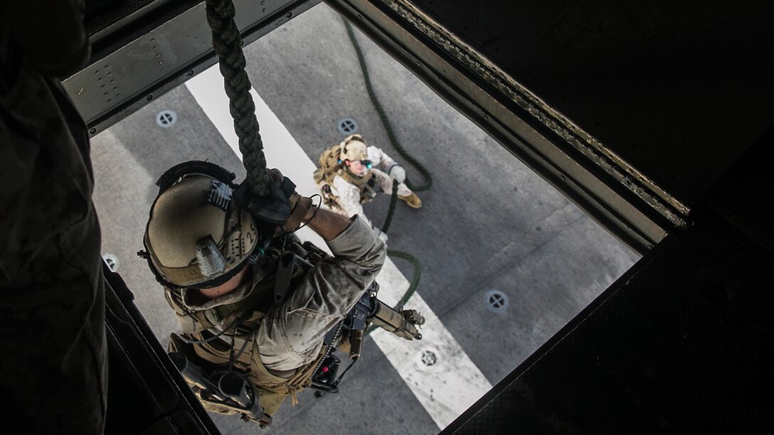 A U.S. Marine with the 15th Marine Expeditionary Unit’s Maritime Raid Force fast-ropes out of a CH-53E Super Stallion onto the flight deck of the USS Essex (LHD 2) at sea in the Indian Ocean, June 17, 2015. These Marines are trained to immediately set up a security posture once they hit the deck to ensure they are watching out for the Marines sliding down the rope. 