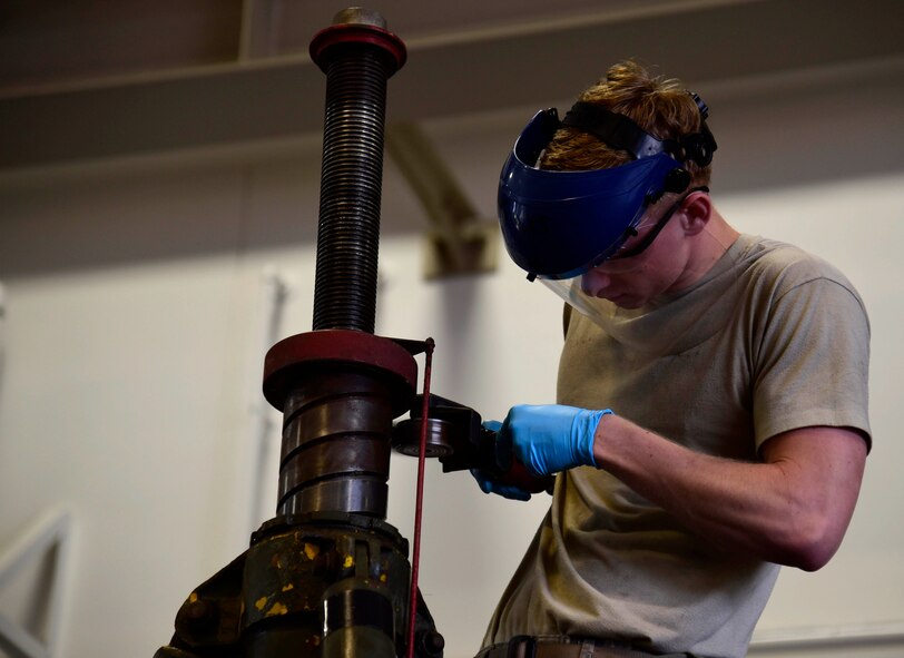U.S. Air Force Airman 1st Class Thomas Nugent, 35th Maintenance Squadron aerospace ground equipment journeyman, uses a crud thug to remove rust from a jack for changing aircraft tires at Misawa Air Base, Japan, June 17, 2015. AGE Airmen conduct cleaning and maintenance of flightline equipment to ensure optimal performance. (U.S. Air Force photo by Airman 1st Class Jordyn Fetter/Released)