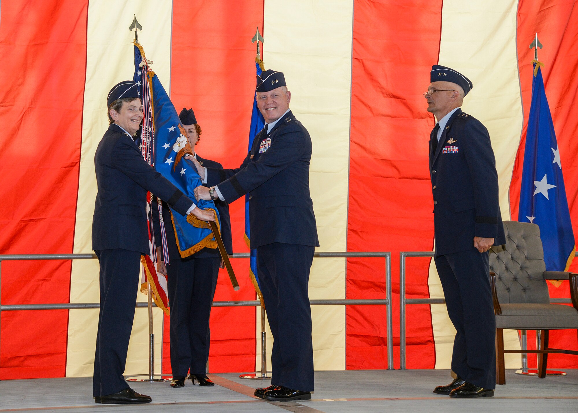 General Ellen Pawlikowski, commander of Air Force Materiel Command, hands the Air Force Test Center guidon to Maj. Gen. David Harris June 18. Harris assumed command from Maj. Gen. Arnold W. Bunch Jr. (right) during a change of command ceremony held in Hangar 1600 June 18. (U.S. Air Force photo by Rebecca Amber)