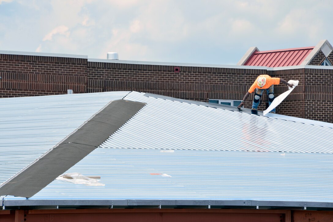 McGHEE TYSON AIR NATIONAL GUARD BASE, Tenn. - A construction worker installs a temporary ice and water barrier along the seams of the tin sub-roof atop the new classroom building here, June 16, 2015. The barrier will be in place until installation of the permanent standing-seam metal roof later this month. (U.S. Air National Guard photo by Master Sgt. Jerry D. Harlan/Released)