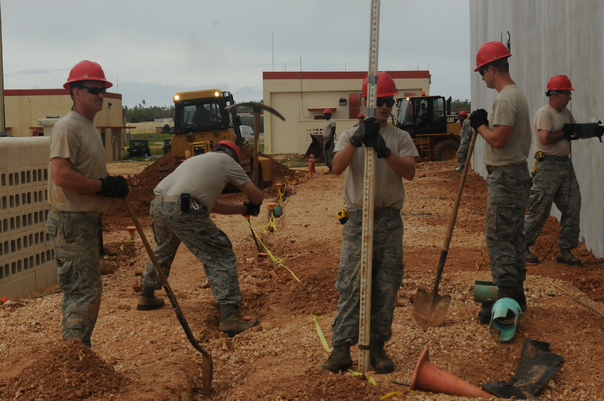 Airmen from the Virginia Air National Guard’s Virginia Beach-based 203rd RED HORSE Squadron and the 202nd RHS from Camp Blanding, Florida refine and train upon essential skills June 3, 2015 during a joint training mission to erect a Facilities Systems Training facility at Anderson Air Force Base, Guam. The Airmen are conducting training while building the FST facility under the Air National Guard’s Deployment for Training program. Airmen in this photo demonstrate several skills such as site grading and restoration to improve drainage, drilling holes for installation of an electrical meter, digging a trench to connect the grounding for the Lightening Protection System, and site elevation to ensure the LPS is 12 inches below final grade. (U.S. Air National Guard photo by Tech. Sgt. Meghan Skrepenski /Released)