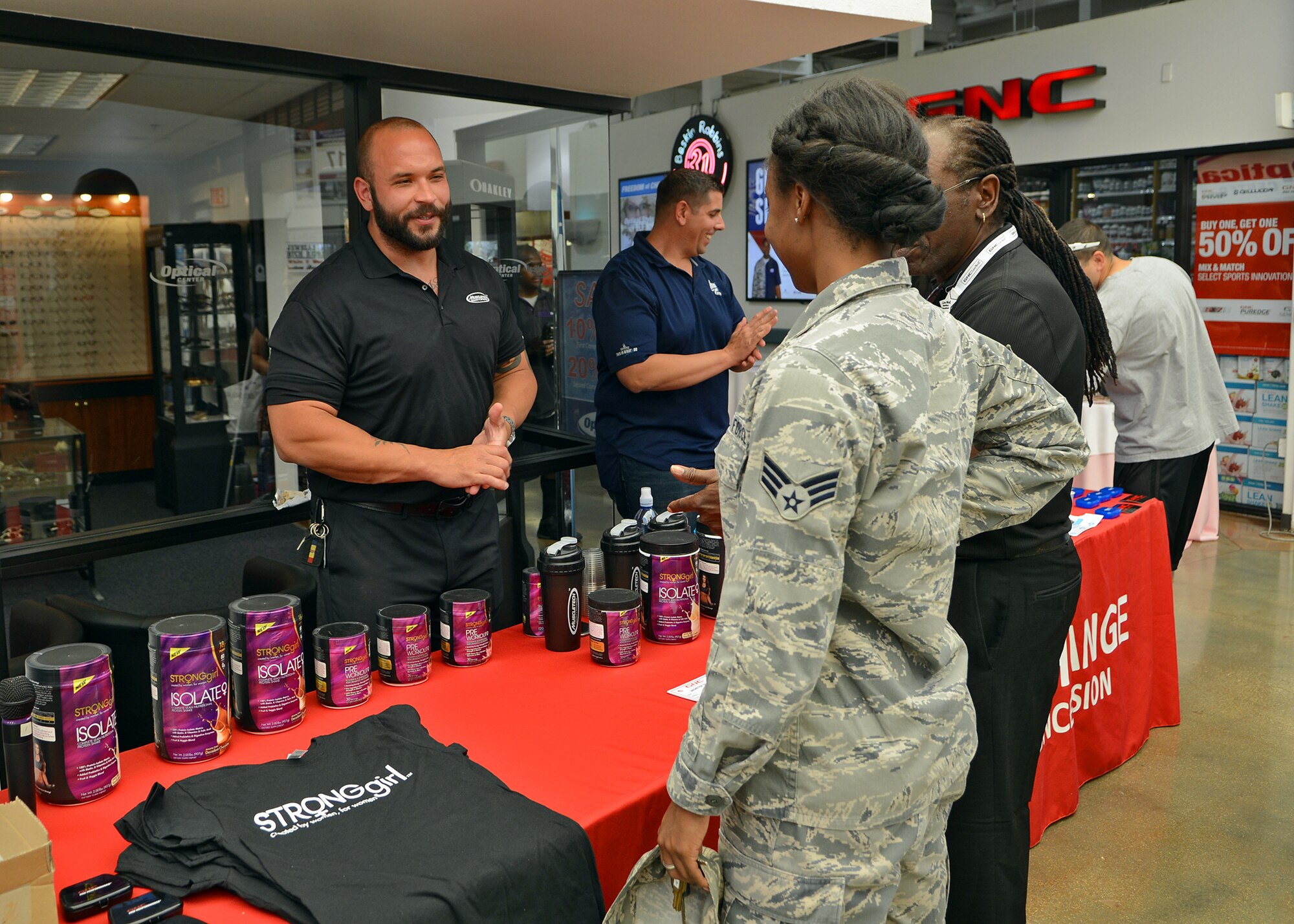 Ryan Warner, Muscletech sales representative, speaks to a servicemember during a women’s health event to promote fitness at the installation that was hosted by GNC and local vendors at the Base Exchange June 15. Muscletech , BPI Sports, Stylique Salon, Tupperware, Allied Physical Medicine and National Physique Committee figure competitor, Stephanie Johnson, were among those in attendance during the event. (U.S. Air Force photo by Jet Fabara)