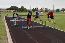 Competitors run a 100 meter hurdle race on Laughlin Air Force Base, Texas, June 13, 2015. Dorm residents, Senior Airman and below, created teams of four to compete in the first ever Laughlin Dorm Olympics to win prizes and to claim first place. (U.S. Air Force photo by Airman 1st Class Brandon May)