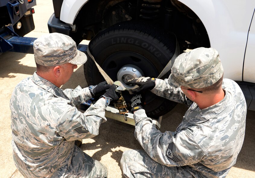 Tech. Sgt. James Baggott, 403rd Logistics Readiness Squadron vehicle control officer from Keesler Air Force Base, Miss., and Staff Sgt. John McCaw, 2nd LRS vehicle operator, secure a wheel of a pickup truck on Barksdale Air Force Base, La., June 12, 2015. When P5 deployment tempos begin October 1, 2015, 2nd LRS is anticipating a significant manpower loss, so it's critical to have capable, experienced people ready to ensure the mission moves forward. (U.S. Air Force photo/Airman 1st Class Curt Beach)