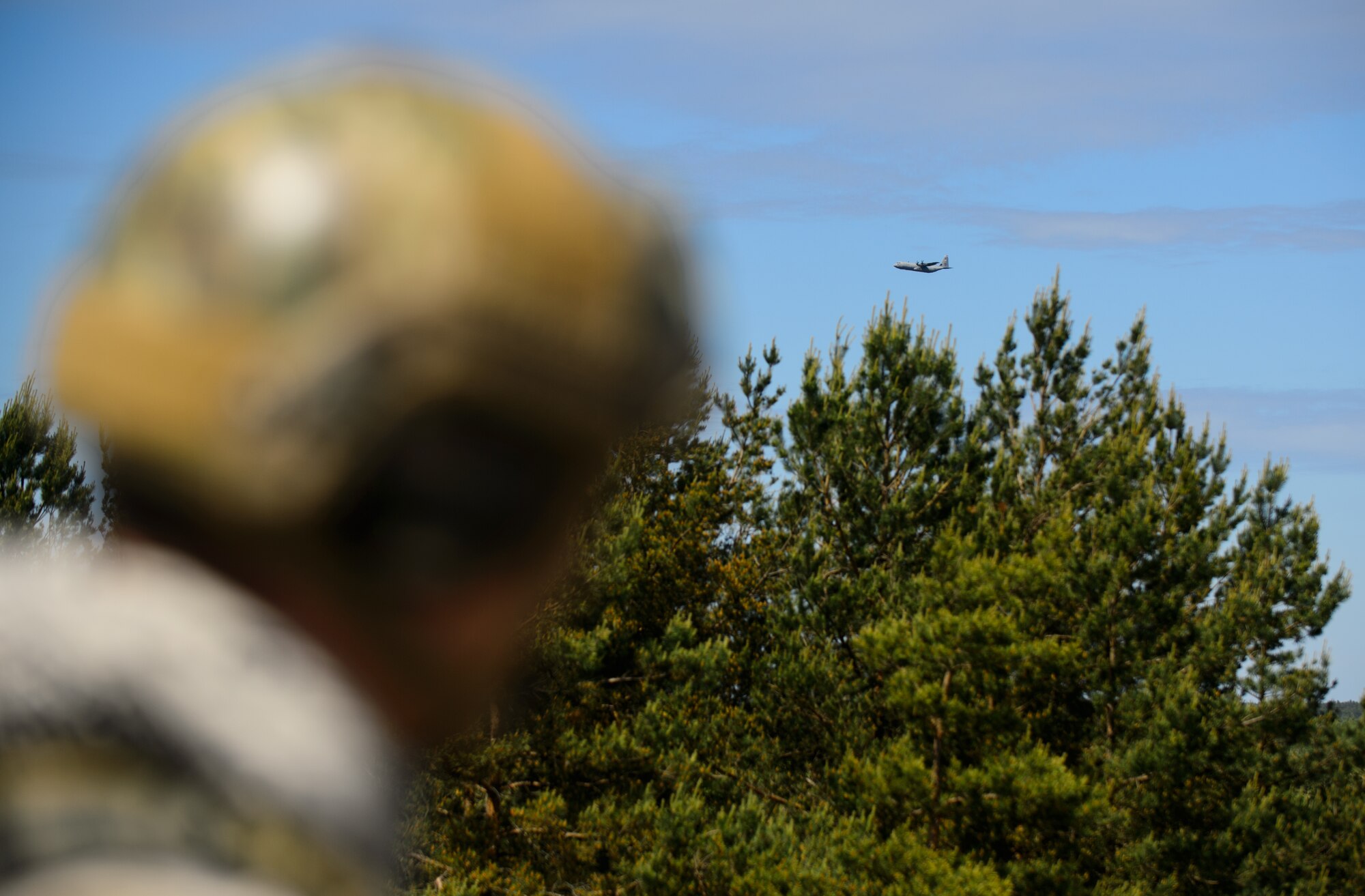 A joint terminal attack controller from the Washington Air National Guard watches a C-130J Super Hercules from the 86th Airlift Wing prepare to drop cargo at Adazi Training Area, Latvia, June 12, 2015. JTACs from various units around the Air Force joined exercise Saber Strike 15 to work with ally and partner nation counterparts to provide precise and directed aircraft support to Army units participating in the exercise. Saber Strike 15 is a multinational exercise with over 6,000 service members learning from each other and helping promote stability in the Baltic region. (U.S. Air Force photo/ Staff Sgt. Armando A. Schwier-Morales)