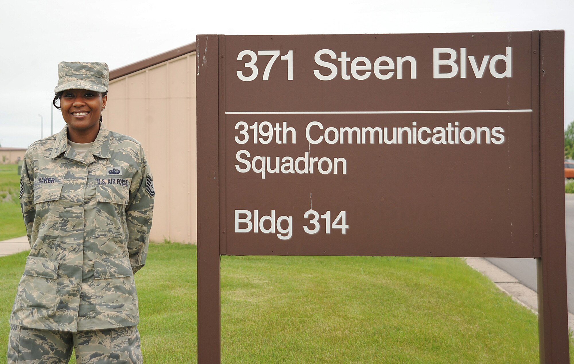 Tech. Sgt. Chenika Baker, 319th Communications Squadron NCO-in-charge, high frequency global communications system (HFGCS) bravo element, stands next to the 319th CS sign on Grand Forks Air Force Base, N.D., June 17, 2015. Baker was selected Warrior of the Week for the third week in June. (U.S. Air Force photo by Airman 1st Class Bonnie Grantham/Released)