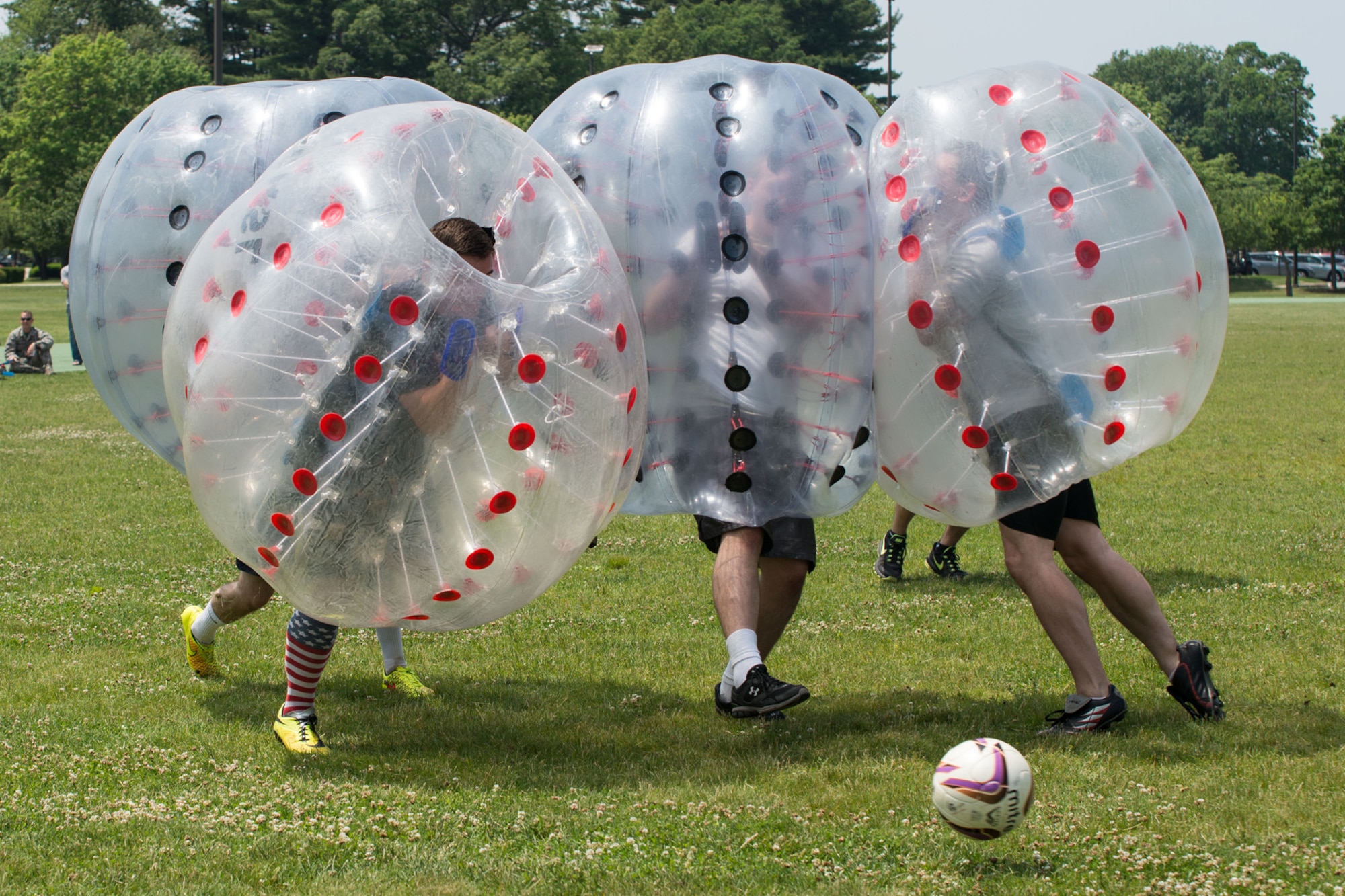 A member of the 66th Security Forces Squadron bubble soccer team (black dots) collides with opposing players from the JSTARS Recap Division team (red dots) while going for the ball during a bubble soccer tournament at the base track June 12. The Hanscom Air Force Sergeants Association planned the event as a fundraiser for the organization. (U.S. Air Force photo by Mark Herlihy)