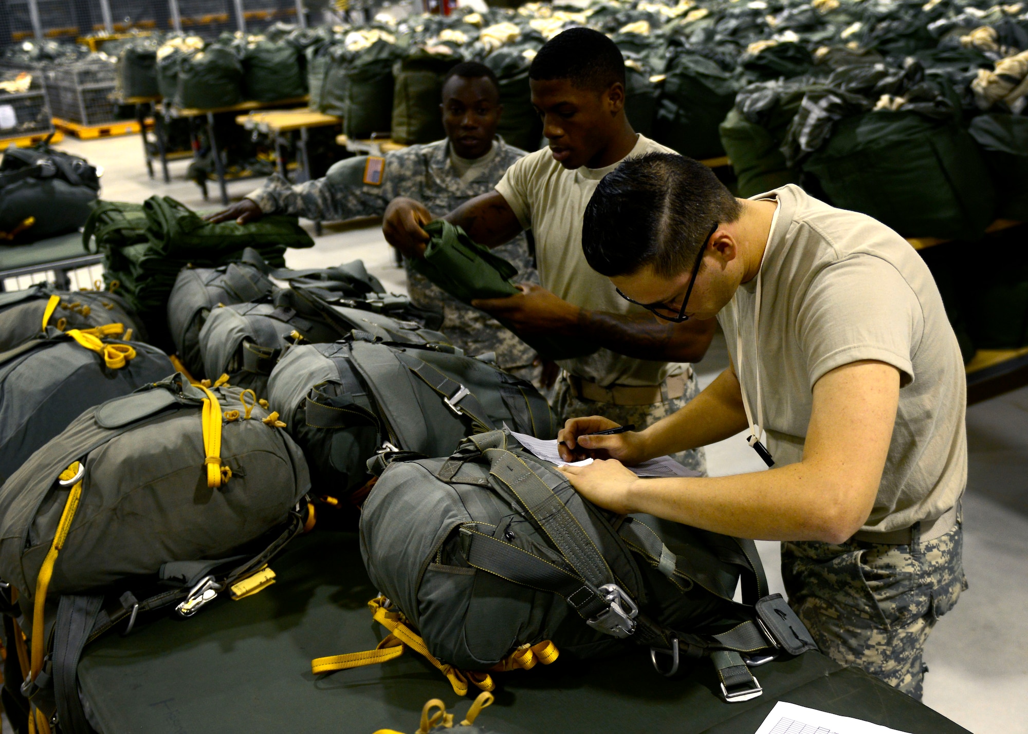 U.S. Army parachute riggers assigned to the Headquarters and Headquarters Company 173rd Brigade Support Battalion ensure parachutes are properly packed, June 17, 2015, at Aviano Air Base, Italy. The unit packs more than 2,400 parachutes a month in preparation for jumps. (U.S. Air Force photo by Senior Airman Areca T. Wilson/Released)