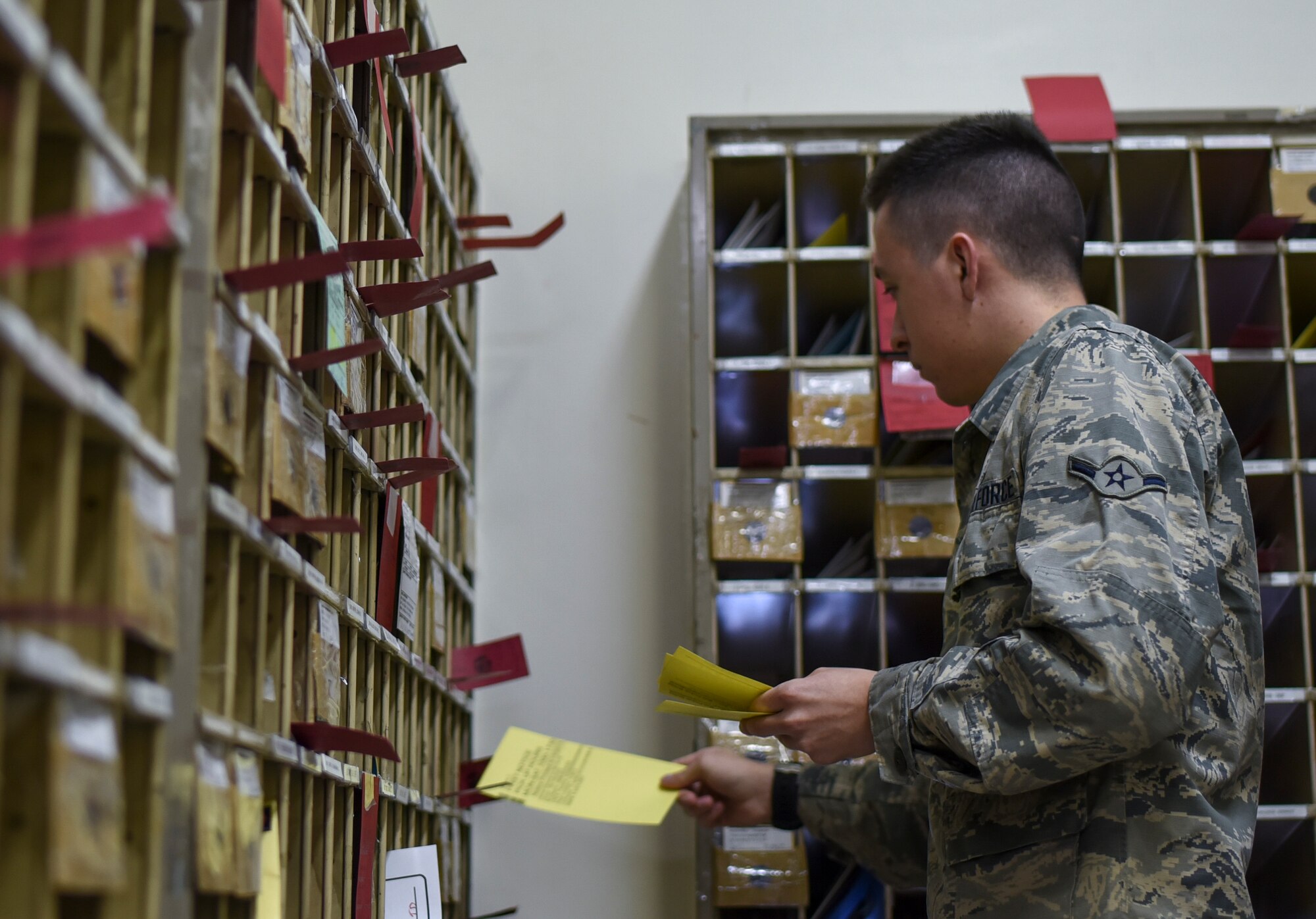Airman Tristan Dobbins, 374th Communication Squadron Post Office postal clerk, drops off yellow delivery slips into mailboxes at Yokota Air Base, Japan, June 15, 2015. Dobbins estimates that they drop off 200 to 300 slips per day. (U.S. Air Force photo by Senior Airman Michael Washburn/Released)
