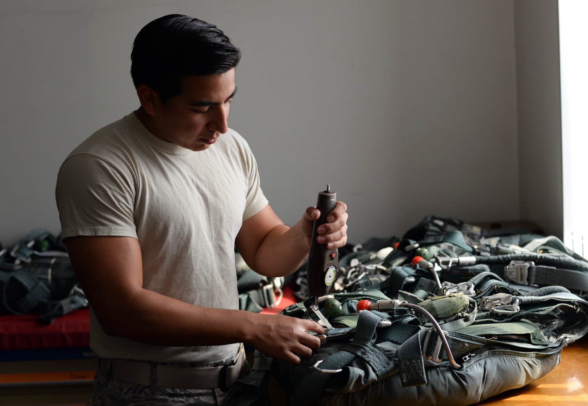 Staff Sgt. David Gutierrez, 374th Operations Support Squadron aircrew flight equipment supervisor, uses a torque device to measure the resistance of a parachute backpack clamp at Yokota Air Base, Japan, June 16, 2015. The backpacks need to be inspected every 30 days to ensure they are of the highest standard to keep the aircrew safe. (U.S. Air Force photo by Senior Airman Michael Washburn/Released)
