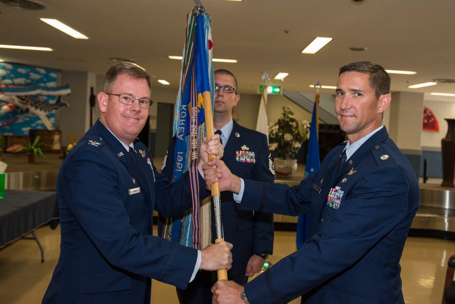 U.S. Air Force Col. Dale “Lee” Landis II, 515th Air Mobility Operations Group commander, passes the guidon to Lt. Col. Shanon Anderson, 733rd Air Mobility Squadron commander, as he accepts command of the squadron during a change of command ceremony on Kadena Air Base, Japan, June 11, 2015. As commander Anderson will lead more than 240 American and Japanese, civilian and military personnel in generating, launching and recovering air mobility missions in order to deploy, receive and sustain American and allied combat forces. (U.S. Air Force photo by Senior Airman Stephen G. Eigel)