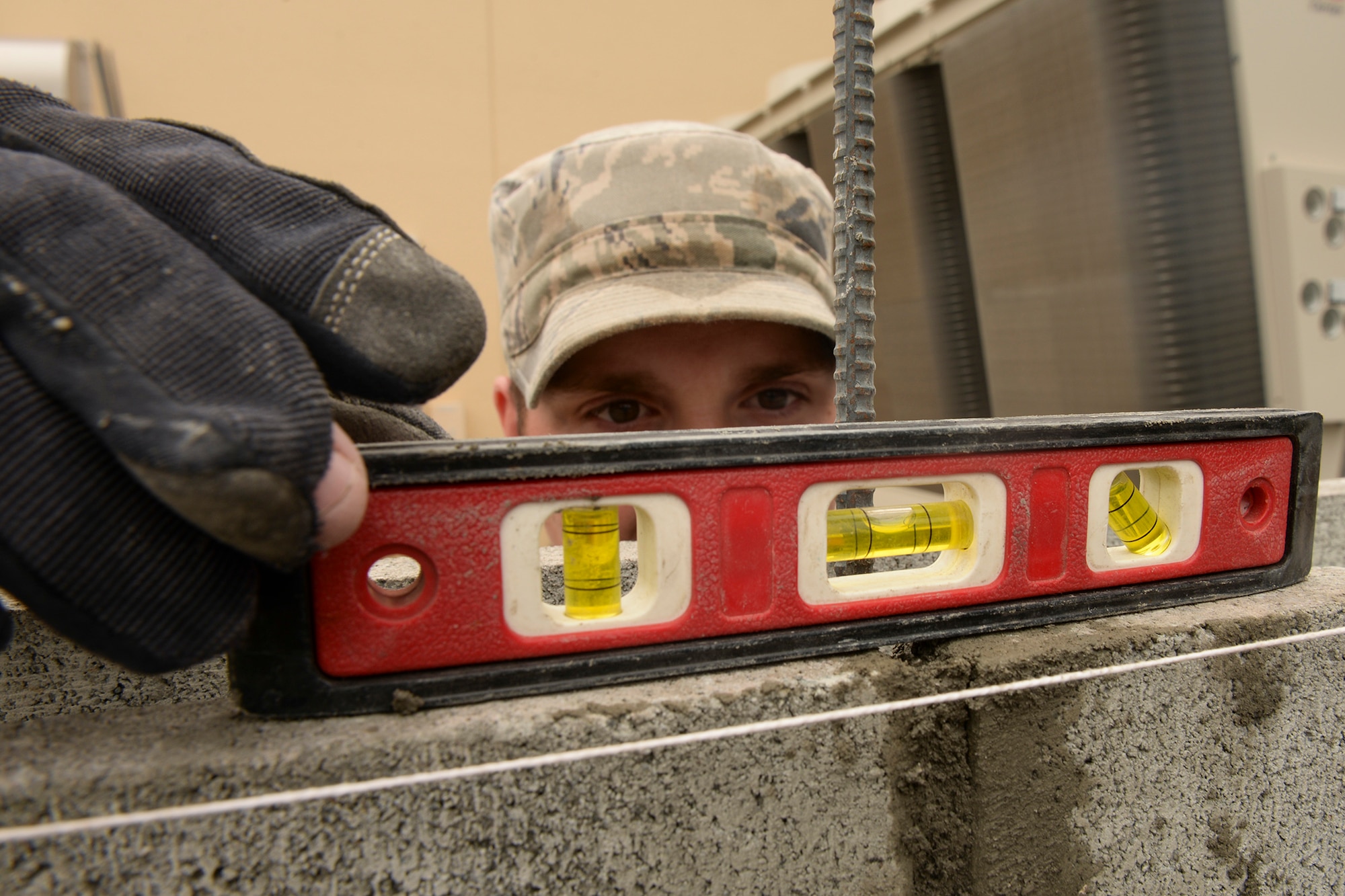 Airman 1st Class Tristan Fournier, 374th Civil Engineer Squadron structural journeyman, uses a level to test the placement of a cinder block he has just laid at Yokota Air Base, Japan, June 16, 2015. The 374 CES structural Airmen support Yokota by building, sustaining, and maintaining structures on base. (U.S. Air Force photo by Airman 1st Class Elizabeth Baker/Released)