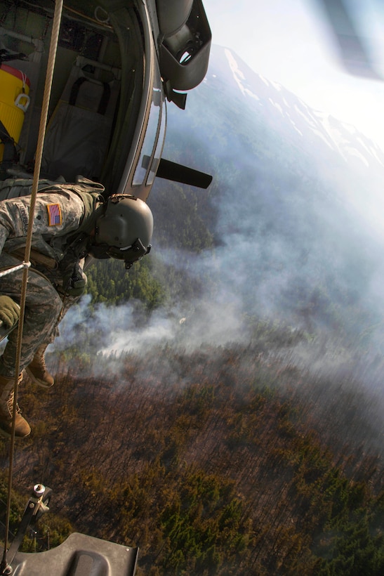 A UH-60 Black Hawk helicopter carries a bambi bucket during firefighting efforts at Russian Lake near Cooper Landing on the Kenai Peninsula in Alaska, June 17, 2015. The helicopter crew, assigned to the Alaska National Guard's 1st Battalion, 207th Aviation Regiment, flew multiple missions and dropped thousands of gallons of water over the fire.