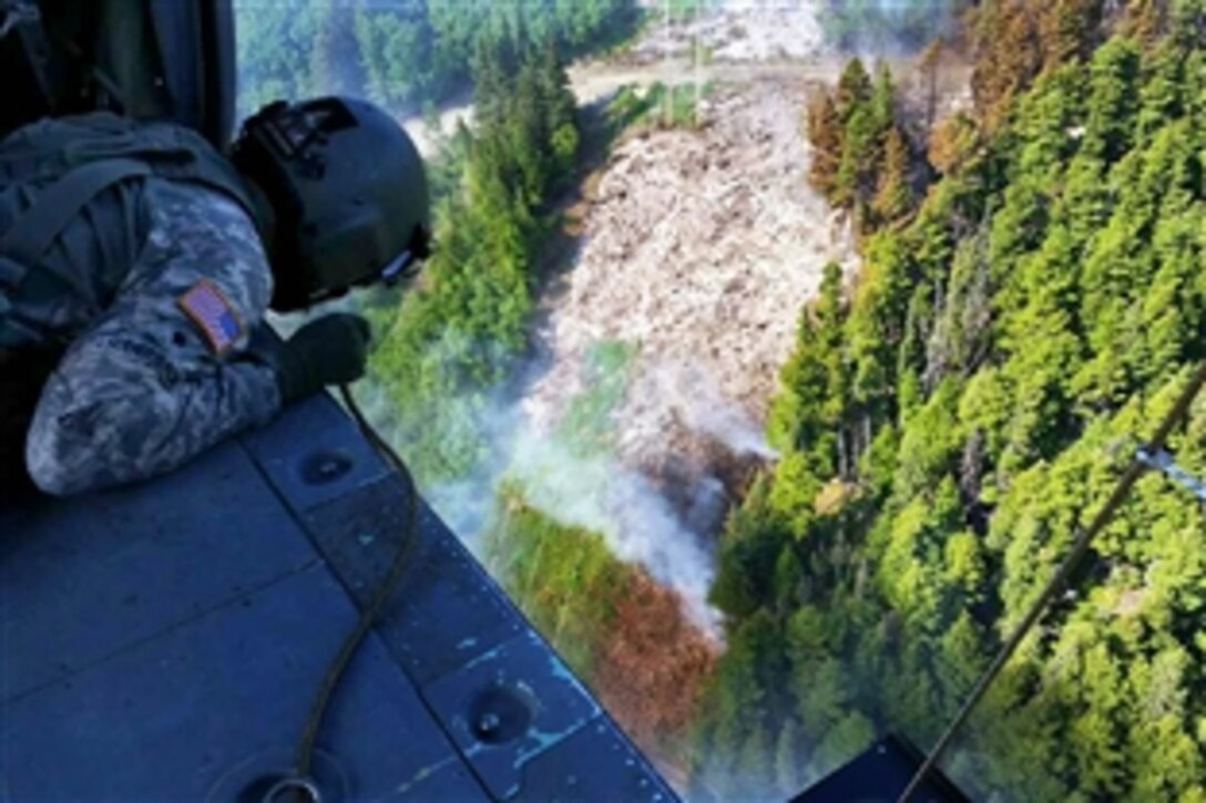Army Spc. Tanner Lauderback watches water drop from a bambi bucket flies to support firefighting efforts at Russian Lake near Cooper Landing, on the Kenai Peninsula in Alaska, June 17, 2015. Lauderback, a crew chief assigned to the Alaska National Guard's 1st Battalion, 207th Aviation Regiment, flew multiple missions as crews dropped thousands of gallons of water over the fire.
