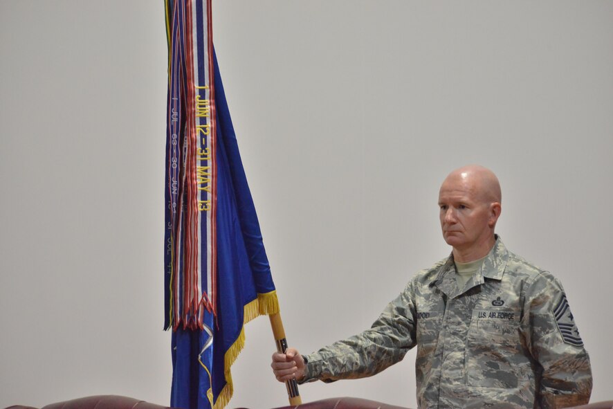 Chief Master Sgt. Thomas Good, 379th Air Expeditionary Wing command chief, holds the wing banner that will be used during the wing change of command June 14, 25015 Al Udeid Air Base, Qatar. Change of commands is a tradition that dates back to the Roman Legion in which authority is transferred from one commanding officer to another and is completed in front of the soldiers.  (U.S. Air Force photo/Staff Sgt. Alexandre Montes)