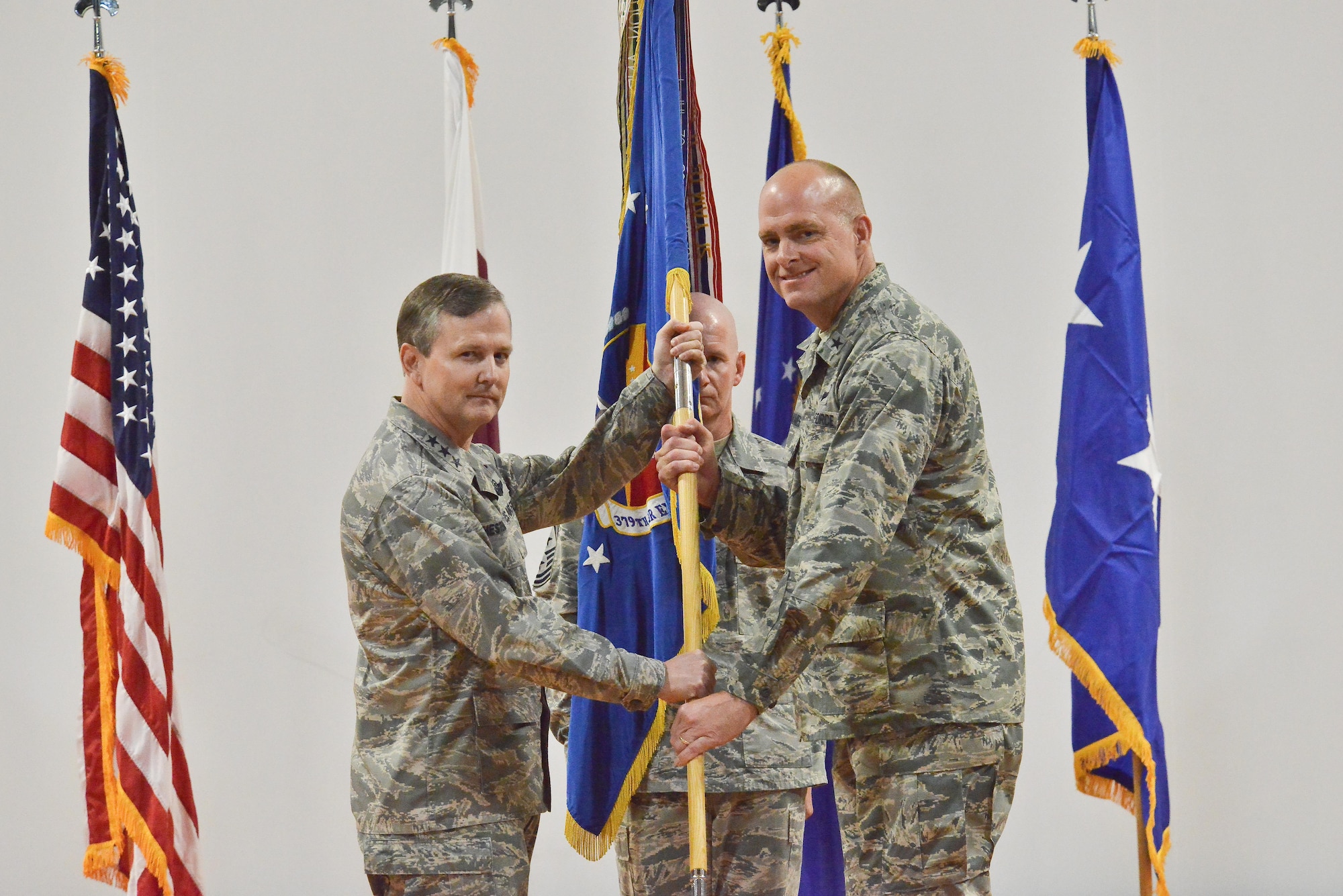 Lt. Gen. John Hesterman, U.S. Air Forces Central Command commander, passes the guidon to Brig. Gen Darren James as he assumes command of the 379th Air Expeditionary Wing June 14, 25015 Al Udeid Air Base, Qatar. Change of commands is a tradition that dates back to the Roman Legion in which authority is transferred from one commanding officer to another and is completed in front of the soldiers.  (U.S. Air Force photo/Staff Sgt. Alexandre Montes)