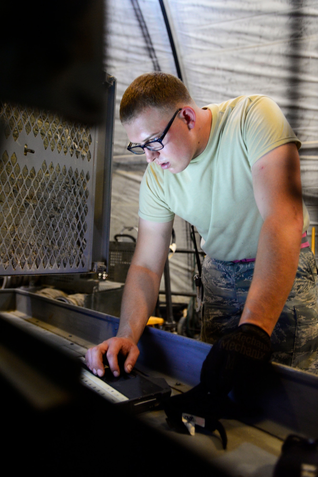 U.S. Air Force Senior Airman Brandon Smith, a 386th Expeditionary Aircraft Maintenance Squadron Aerospace Ground Equipment technician troubleshoots equipment at an undisclosed location in Southwest Asia, June 11, 2015. Smith and Tech. Sgt. Michial Smith deployed together as a father and son duo. (U.S. Air Force photo by Senior Airman Racheal E. Watson/Released)