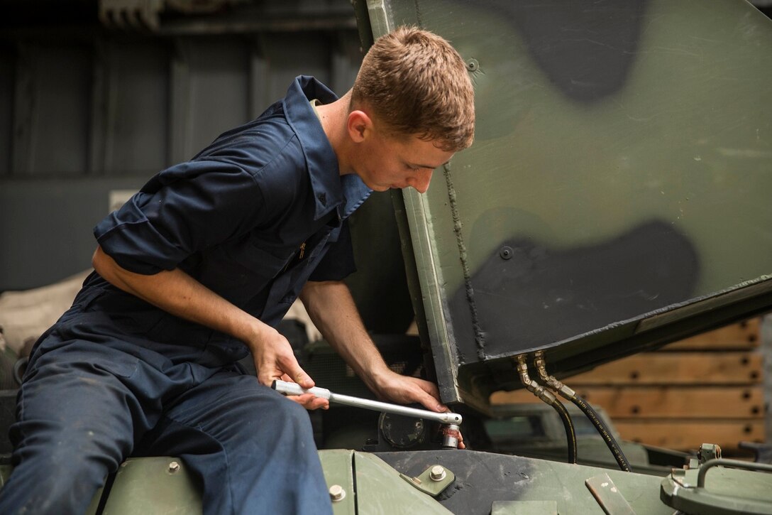 U.S. Marine Cpl. Kevin Versluis loosens bolts on an AAV-7 Amphibious Assault Vehicle during vehicle maintenance aboard USS Rushmore (LSD 47) at sea in the Strait of Malacca, June 15, 2015. Versluis is an AAV crew chief with Kilo Company, Battalion Landing Team 3rd Battalion, 1st Marine Regiment, 15th Marine Expeditionary Unit. Versluis and his crew were replacing the hydrostatic steering unit, a component that controls the vehicle’s steering. (U.S. Marine Corps photo by Sgt. Emmanuel Ramos/Released)