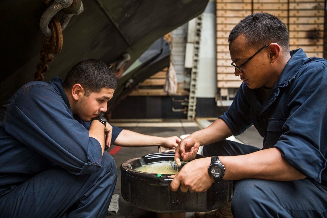 U.S. Marine Lance Cpl. David Medina, left, Lance Cpl. Vicente Cabrera drain the oil from an AAV-7 Amphibious Assault Vehicle during vehicle maintenance aboard USS Rushmore (LSD 47) at sea in the Strait of Malacca, June 15, 2015. Medina and Cabrera are both AAV crewmen with Kilo Company, Battalion Landing Team 3rd Battalion, 1st Marine Regiment, 15th Marine Expeditionary Unit. AAV crewmen were replacing the hydrostatic steering unit, a component that controls the vehicle’s steering. (U.S. Marine Corps photo by Sgt. Emmanuel Ramos/Released)