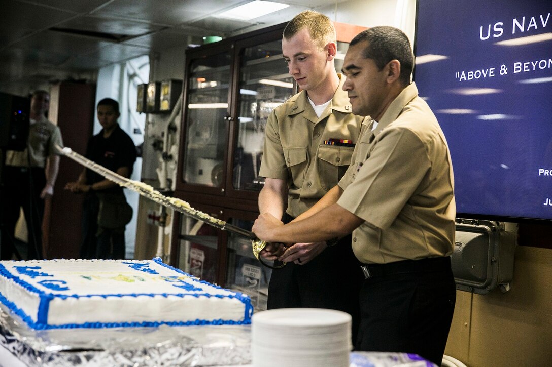 U.S. Sailors and Marines with the Essex Amphibious Ready Group and 15th Marine Expeditionary Unit join to celebrate the Hospital Corps’ 117th birthday aboard the USS Essex (LHD 2) at sea in the Indian Ocean, June 17, 2015. During the ceremony, the oldest and youngest Hospital Corpsman cut the cake together, signifying knowledge passing from the older to the younger generation. (U.S. Marine Corps photo by Cpl. Anna Albrecht/ Released)