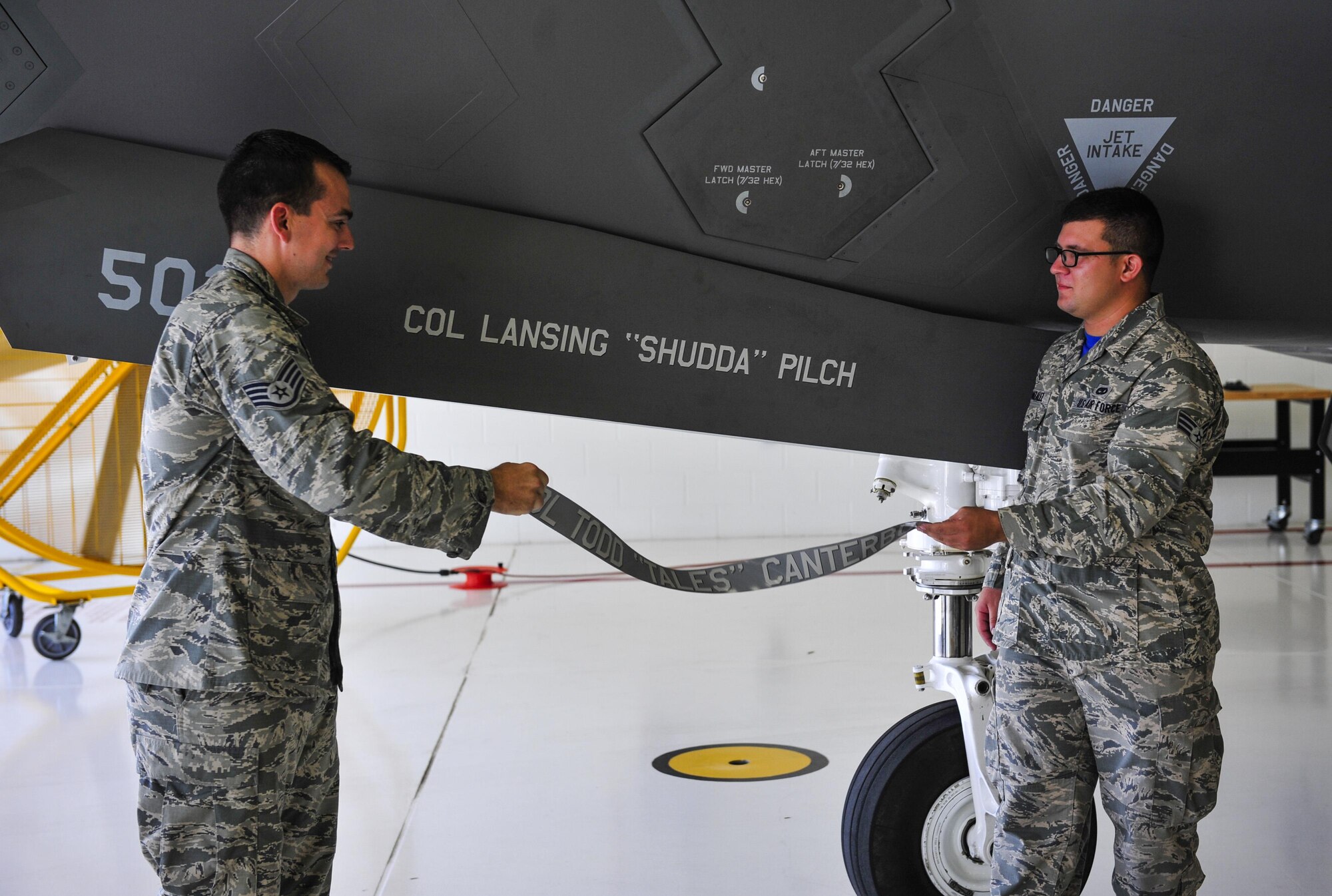 Staff Sgt. Danny Pierera and Senior Airman Mario Gonzalez, 33rd Aircraft Maintenance Squadron dedicated crew chiefs, unveil Col. Lance Pilch’s name on the 33 FW’s flagship, June 19, 2015, on Eglin Air Force Base, Florida. Pilch is a command pilot with more than 2,700 hours in various fighter and heavy aircraft, including more than 900 hours in the F-22A. Prior to arriving here, he served as the commander of the 3rd Operations Group, Joint Base Elmendorf-Richardson, Alaska. (U.S. Air Force photo/Staff Sgt. Marleah Robertson)