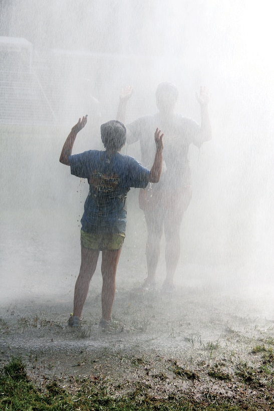 Runners cool off under the fire truck mister during the Run Amuck aboard Marine Corps Base Quantico on Saturday.