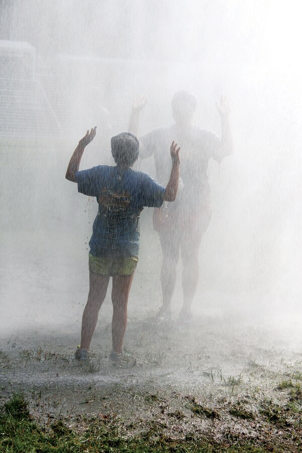 Runners cool off under the fire truck mister during the Run Amuck aboard Marine Corps Base Quantico on Saturday.