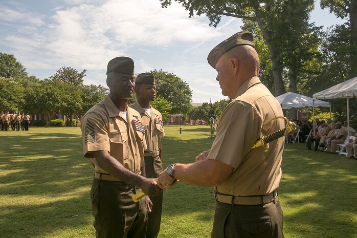 Sgt. Maj. Michael Jones (left) passes his sword to Lt. Gen. Robert Neller (right) during a relief and appointment ceremony aboard Naval Support Activity Hampton Roads, Va., June 19, 2015. The passing of the sword is a tradition in the Marine Corps representing the relinquishment of duties. Jones received the Legion of Merit with gold star and retired after 32 years of service in the Marine Corps. Sgt. Maj. Christopher Robinson (center) assumed the duties of U.S. Marine Corps Forces Command sergeant major. (USMC photo by Steve Kotecki/RELEASED)